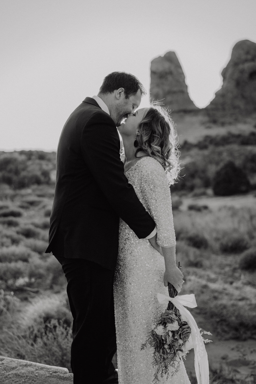 Arches-National-Park-Wedding-Bride-and-Groom-Kiss-at-Sunset-with-rock-spires-on-trail (5).jpg