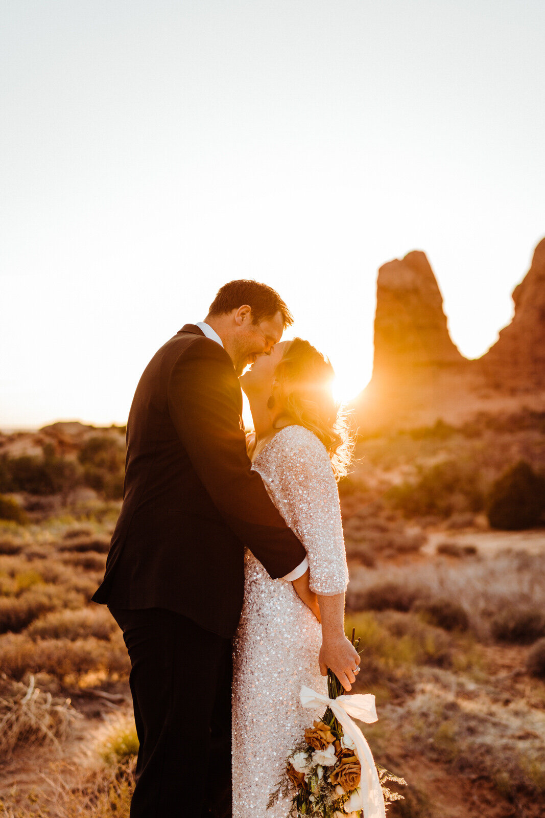 Arches-National-Park-Wedding-Bride-and-Groom-Kiss-at-Sunset-with-rock-spires-on-trail (6).jpg