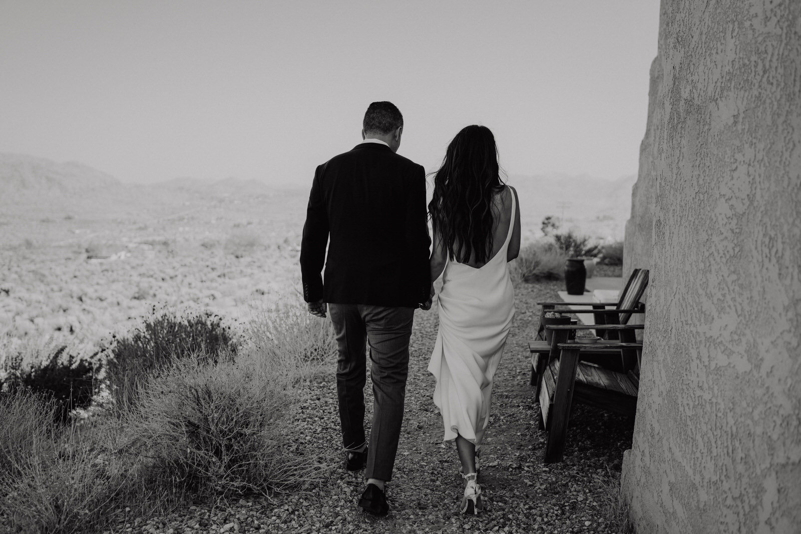 Black and white photo of Bride and Groom walking hand in hand back to Airbnb after first look in Joshua Tree