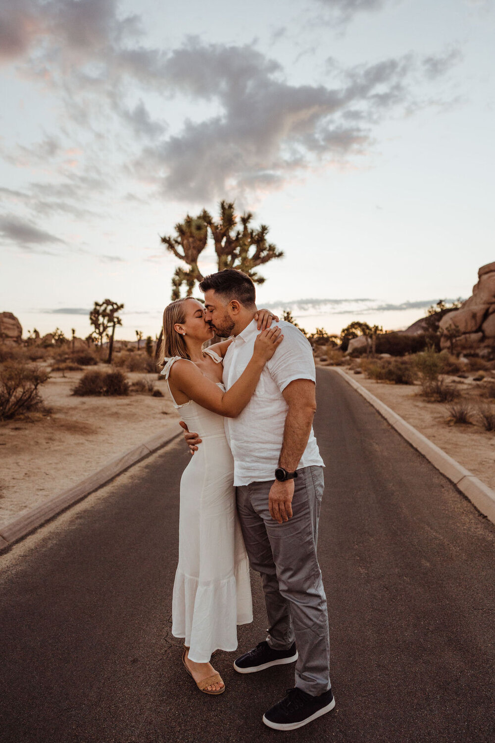 Sunrise Engagement Session in Joshua Tree, California - Man and Woman Kiss in the Middle of the Road - Photos by Adventurous Elopement + Wedding Photographer Kept Record | www.keptrecord.com