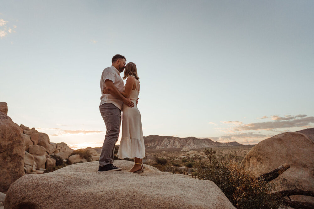 Sunrise Engagement Session in Joshua Tree, California - Couple Stands on Boulder in National Park - Photos by Adventurous Elopement + Wedding Photographer Kept Record | www.keptrecord.com