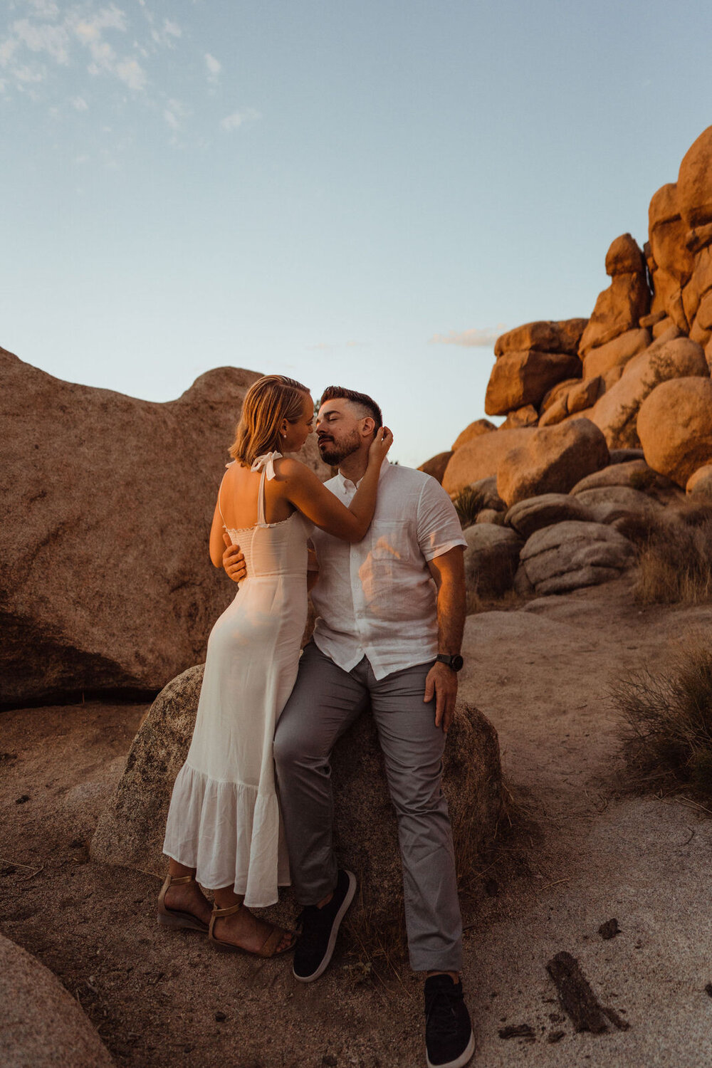 Sunrise Engagement Session in Joshua Tree, California - Woman Leans on Man Sitting on Rock - Photos by Adventurous Elopement + Wedding Photographer Kept Record | www.keptrecord.com
