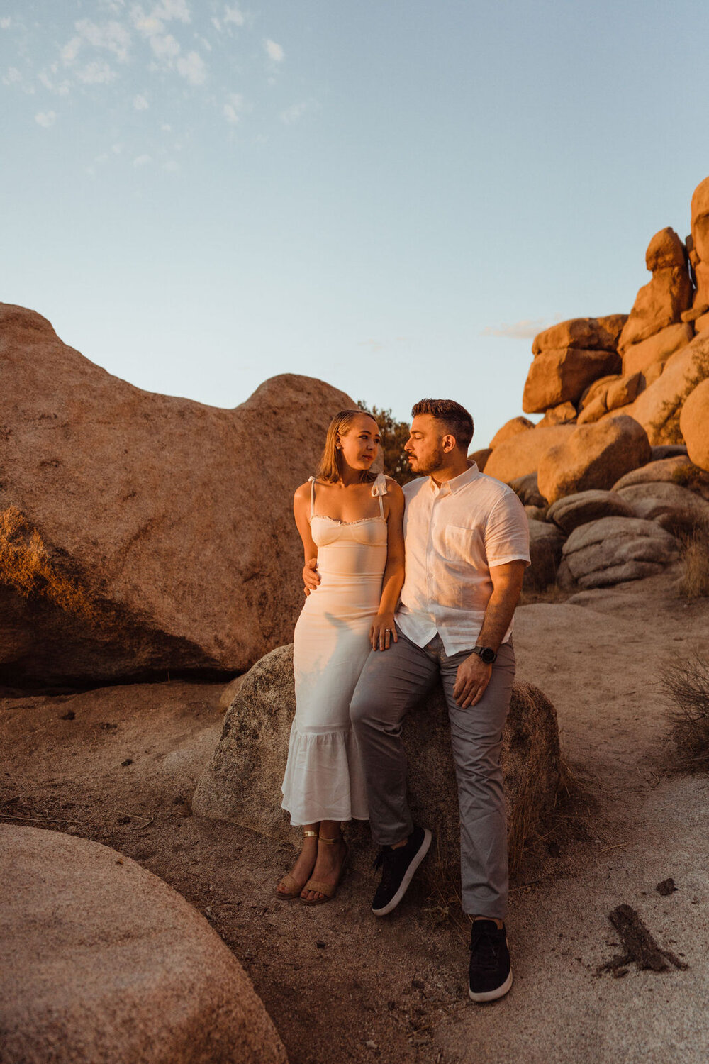 Couple Sits Side by Side in Dramatic Glowing Sunlight - Sunrise Engagement Session in Joshua Tree, California - Photos by Adventurous Elopement + Wedding Photographer Kept Record | www.keptrecord.com