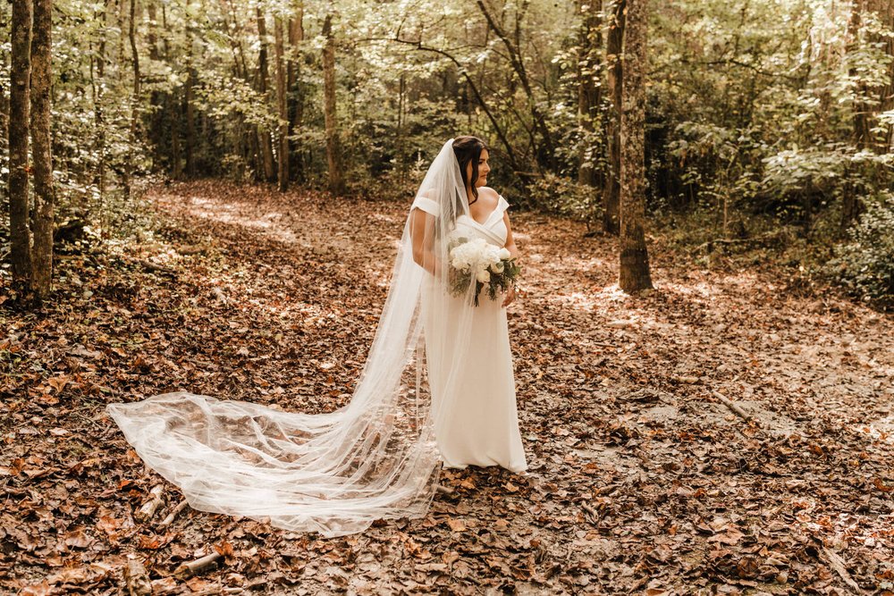 Bride with a long veil stands on a bed of leaves in woodsy, Roswell, Georgia Wedding | Kept Record | www.keptrecord.com