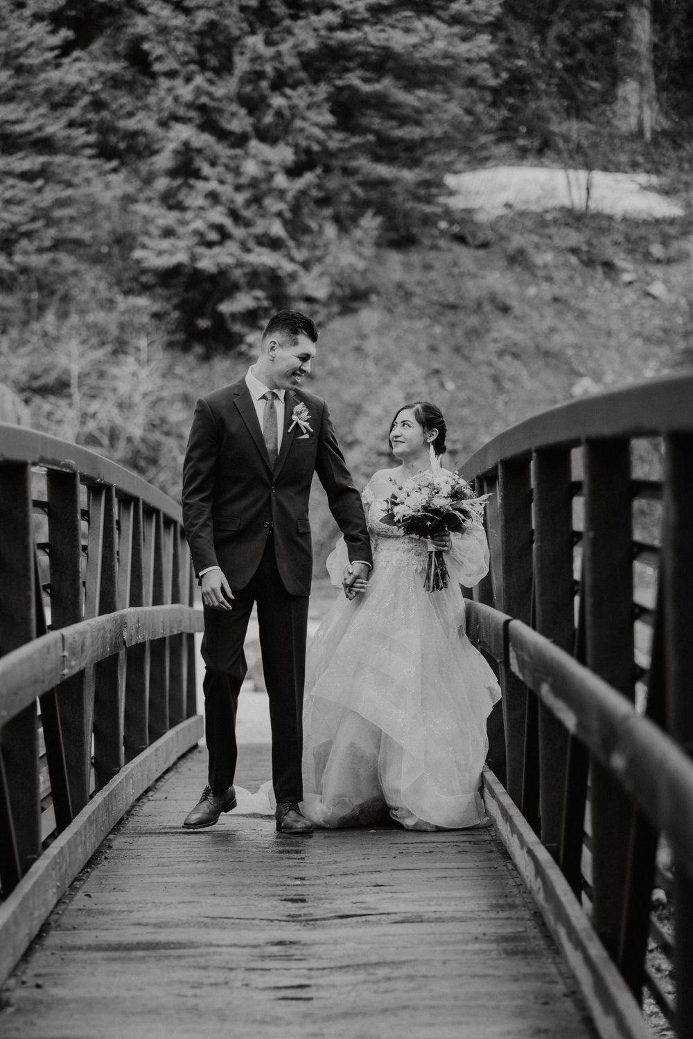 utah-mountain-elopement-bride-and-groom-holding-hands-and-walking-across-bridge.jpg