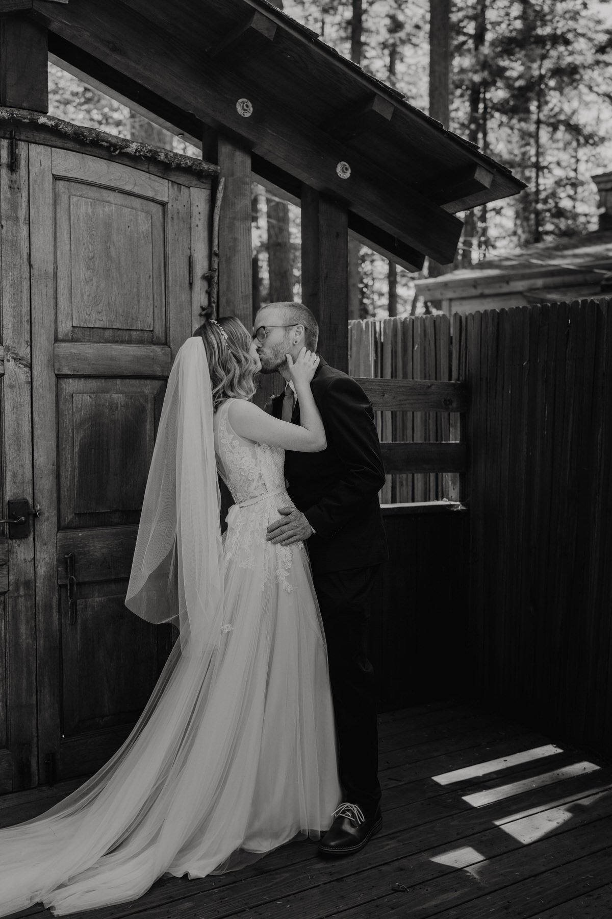 Redwoods-CA-First-Look-Outside-of-Airbnb-Petite-Bride-in-Veil-Kisses-Groom-in-Glasses-in-Black-and-white.jpg