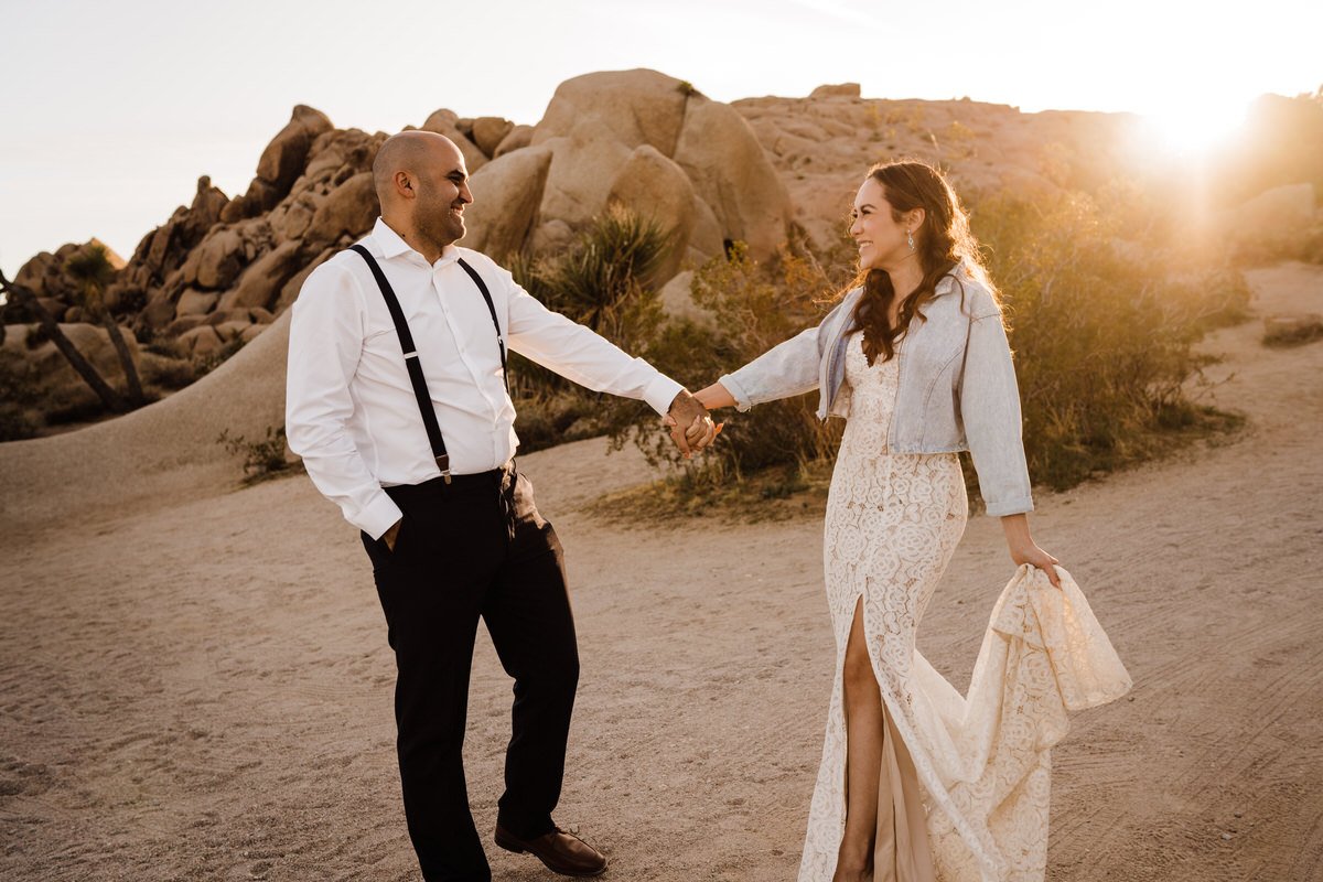 Joshua-Tree-National-Park-Small-Wedding-Playful-Fun-Photo-of-Groom-in-Suspenders-and-Bride-in-Lulus-Dress-with-Jean-Jacket.jpg