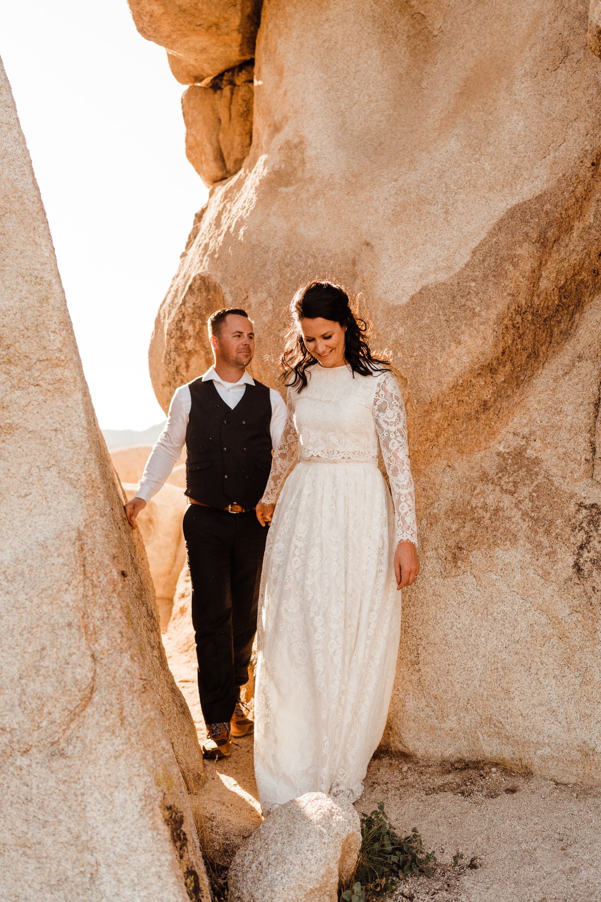 Bride-in-Two-Piece-Wedding-Dress-with-Lace-Sleeves-Leads-Groom-in-Suit-and-Boots.jpg