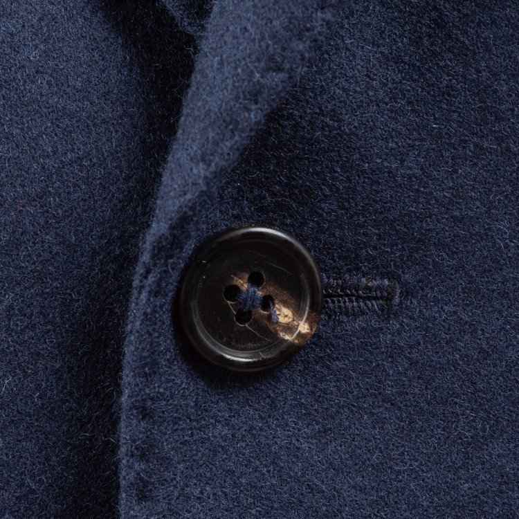 Rolling lapels with pick-stitched edges and brown horn button
