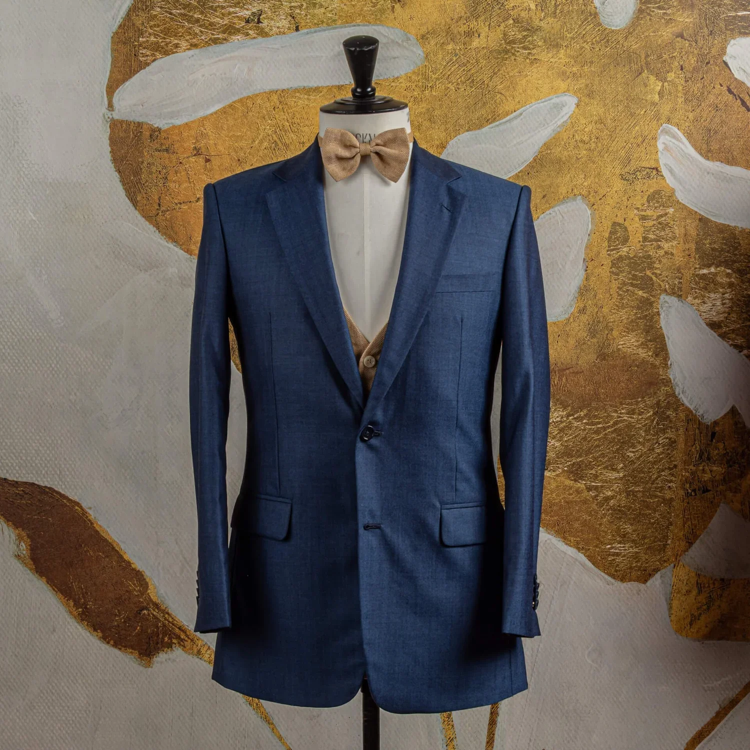 Navy three-piece wedding suit with beige waistcoat and bow tie