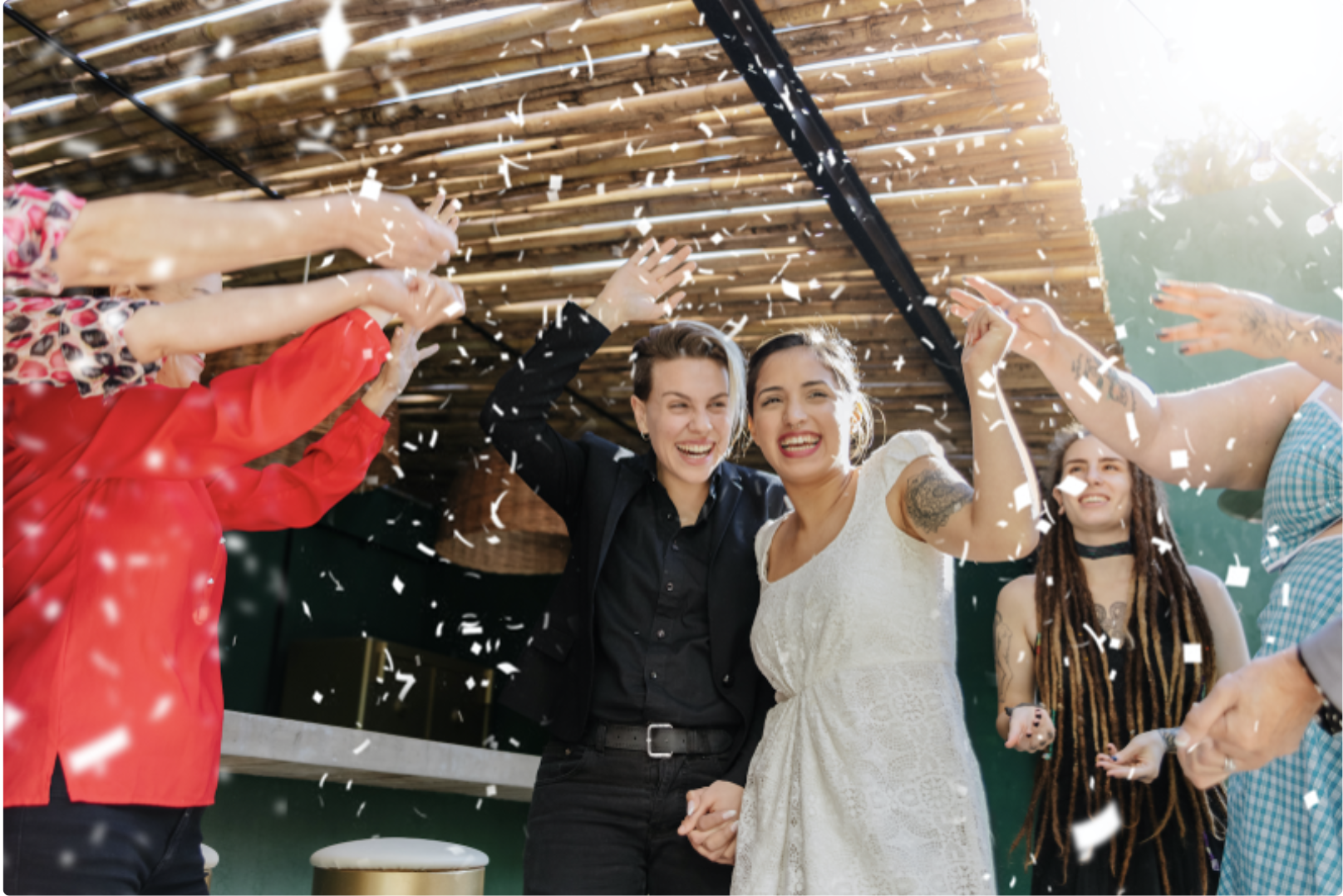 Two women surrounded by well-wishers at their wedding.