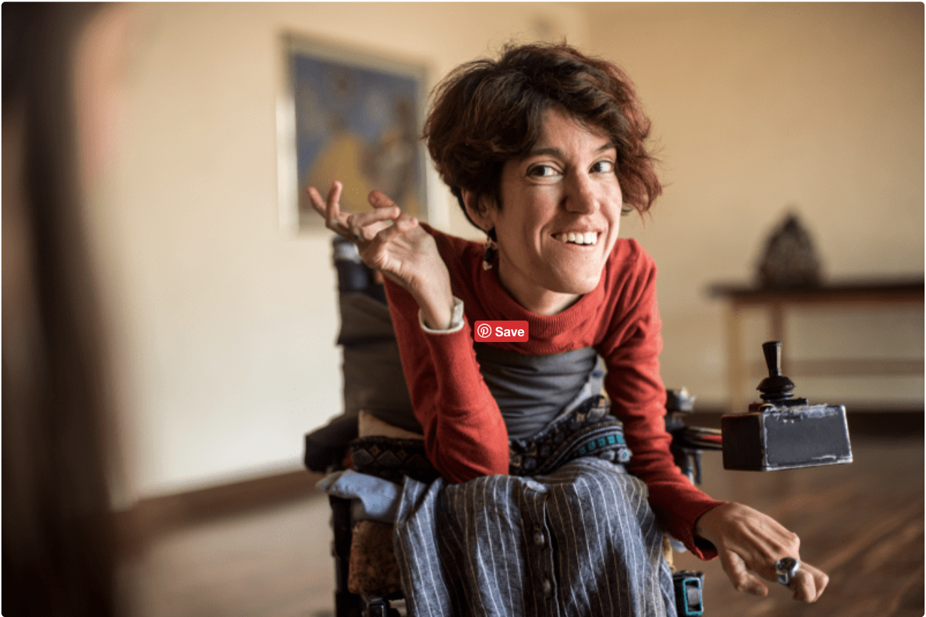 A woman with Spinal Muscular Atrophy in a wheelchair smiling.