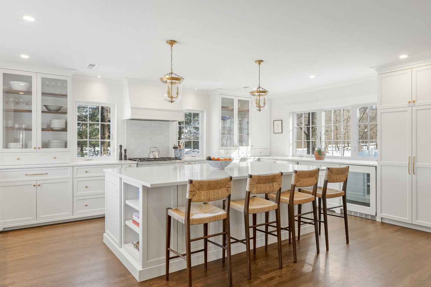 Crisp white cabinetry, brass lighting, warm wood stools, and windows that bring the outside in&mdash;timeless design with a welcoming feel.

Architecture: @winslowdesignarch
Construction: @cutler_building
Structural Engineering: @ssb__engineering
Pho
