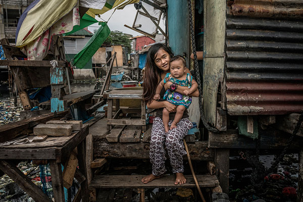  Jasmin Dorana, a 15 year old widow, holds her baby, Hazel, born just a month before her partner, John "Toto" Dela Cruz was pulled by his hair out onto this porch and shot four times in the head and in the chest. Bagung Bayan, C4, Navotas, Metro Mani