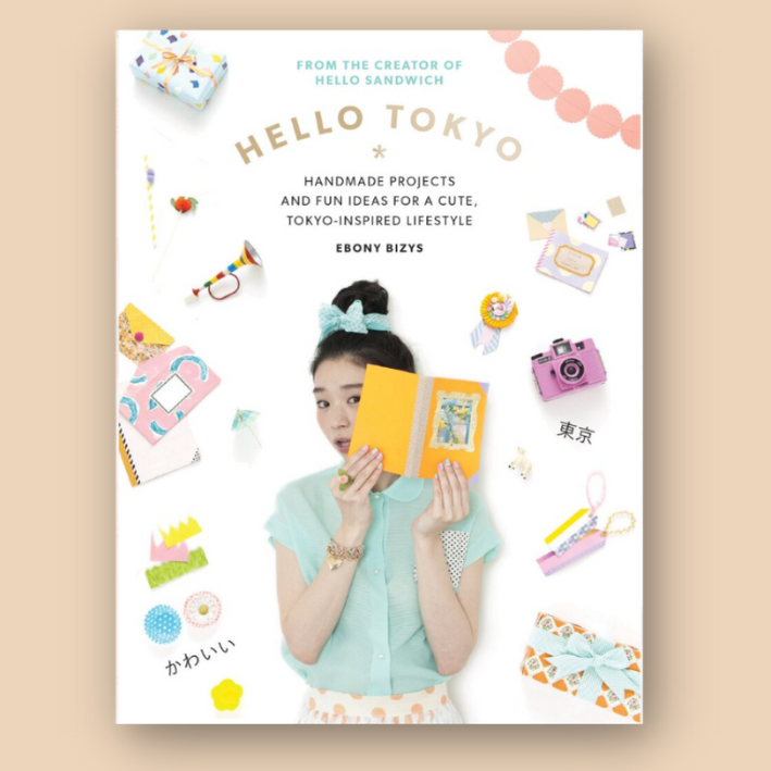 Cover of "Hello Tokyo" by Ebony Bizys, featuring a woman holding a yellow book, surrounded by colorful decorations, crafts, and Japanese text. The subtitle reads "Handmade Projects and Fun Ideas for a Cute, Tokyo-Inspired Lifestyle."