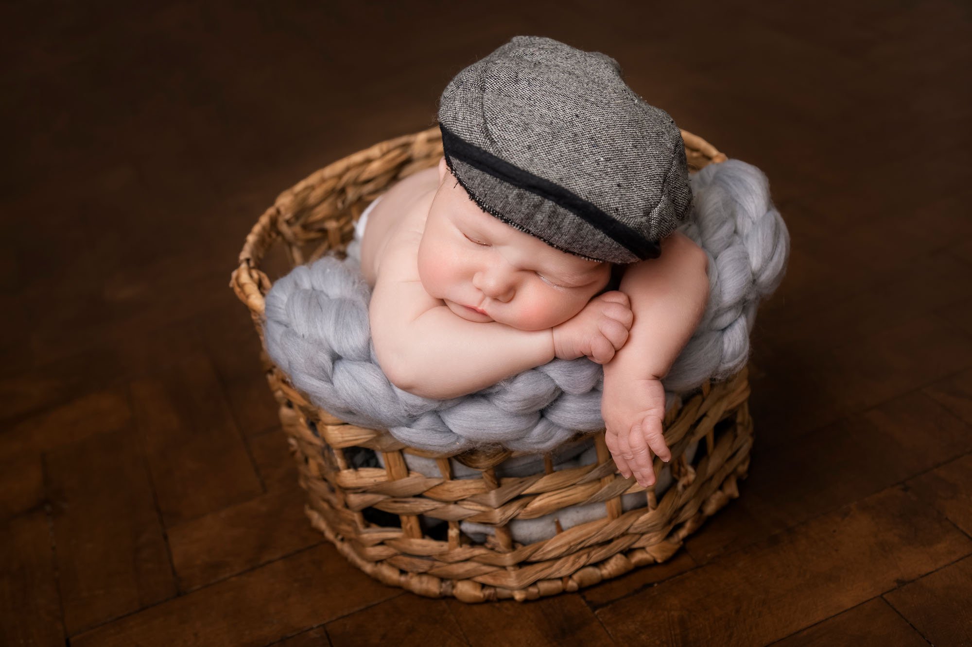 newborn-photography-in-leeds-baby-boy-front-facing-basket-in-flat-cap.jpg