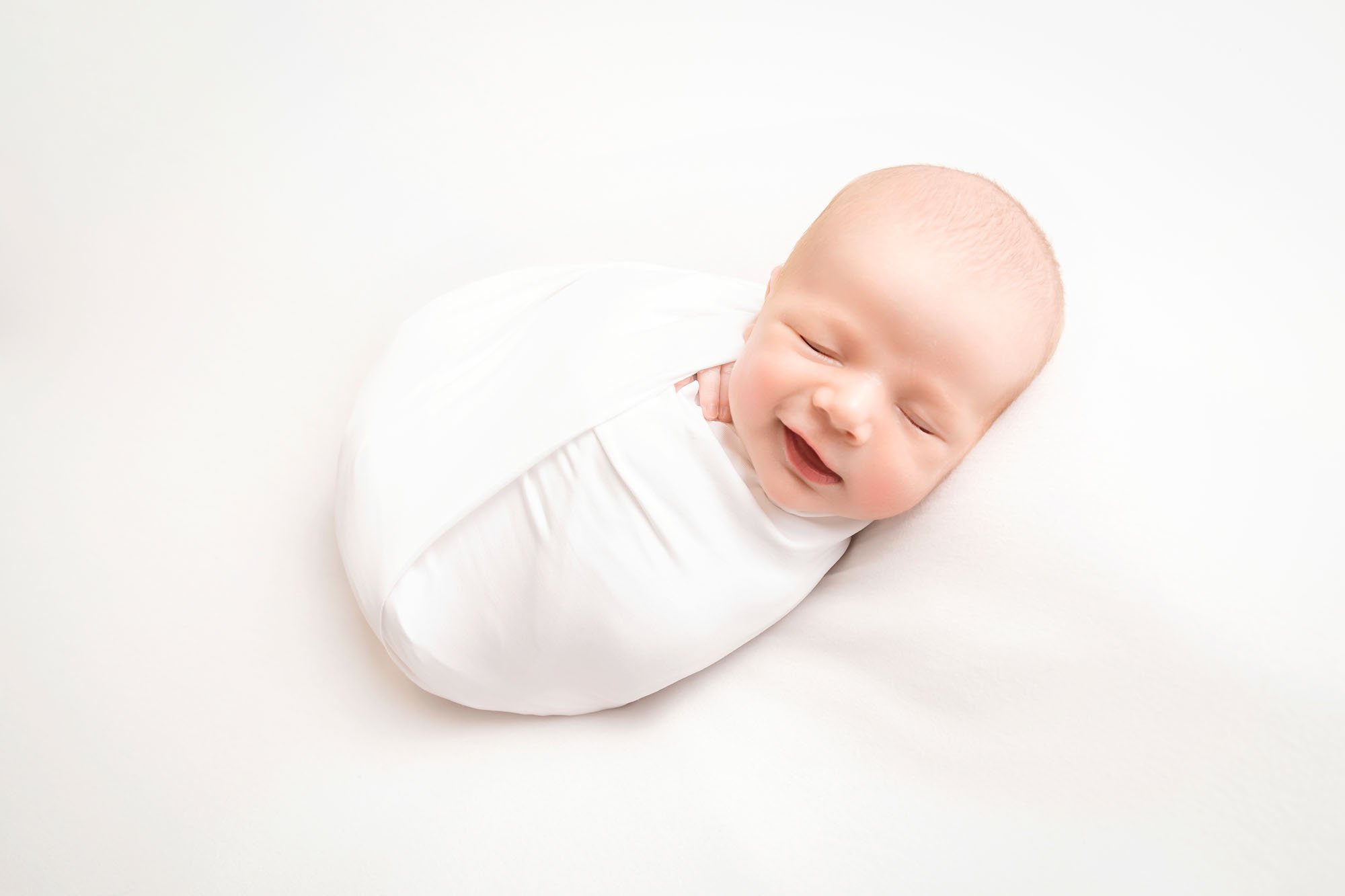 Newborn-photography-in-leeds-baby-swaddled-smiling.jpg
