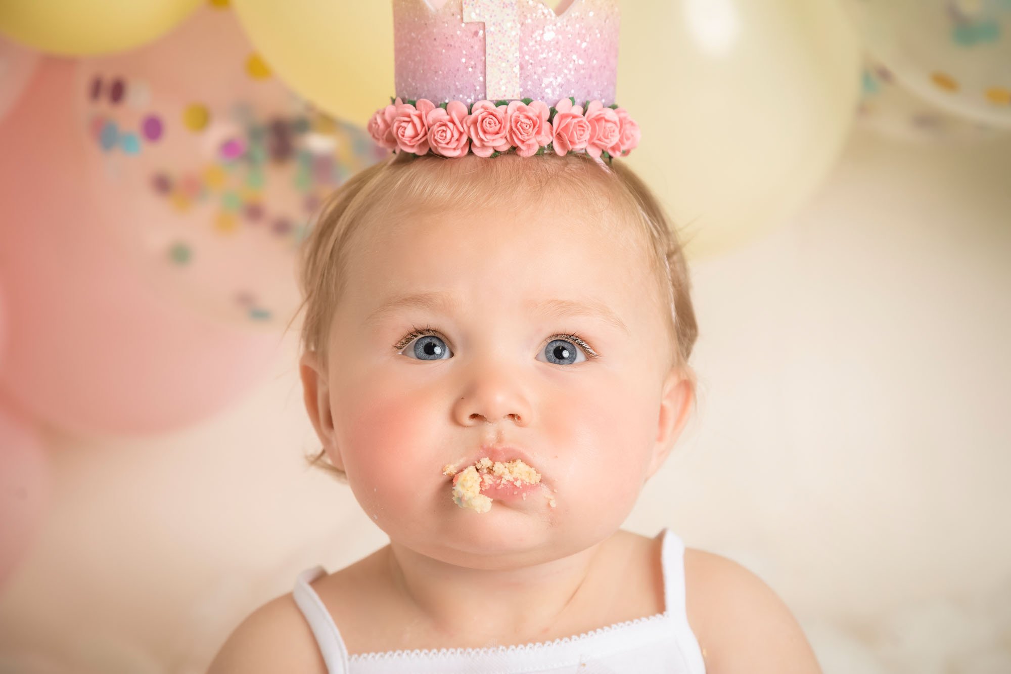 cakesmash-photography-in-leeds-baby-girl-with-mouth-full-of-cake-pastel-rainbow-theme.jpg