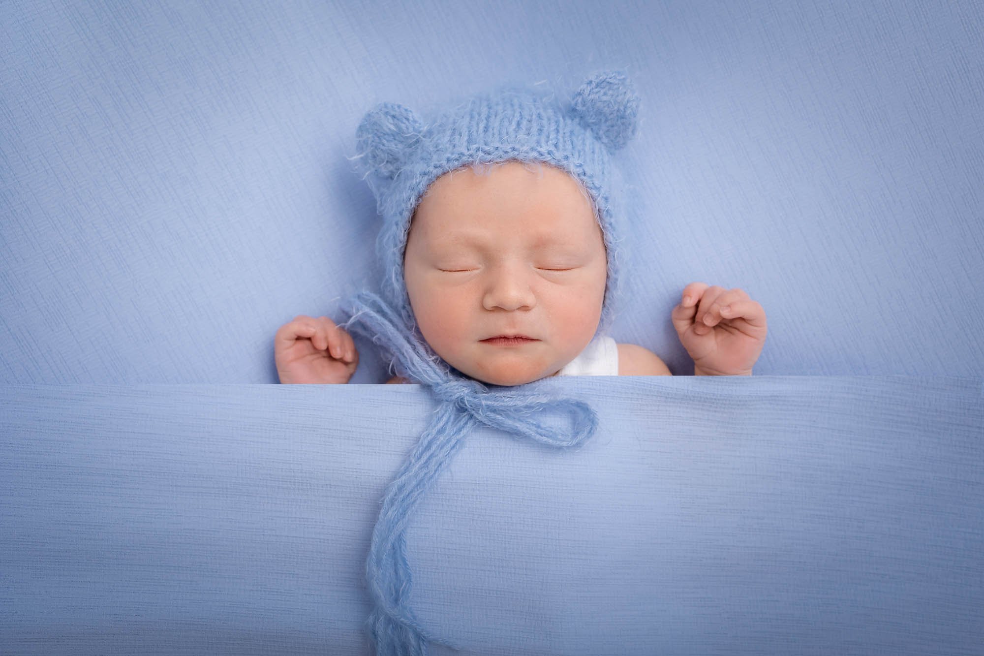 Newborn_photography_in_Leeds_baby_boy_tucked_in_bed_blue.jpg