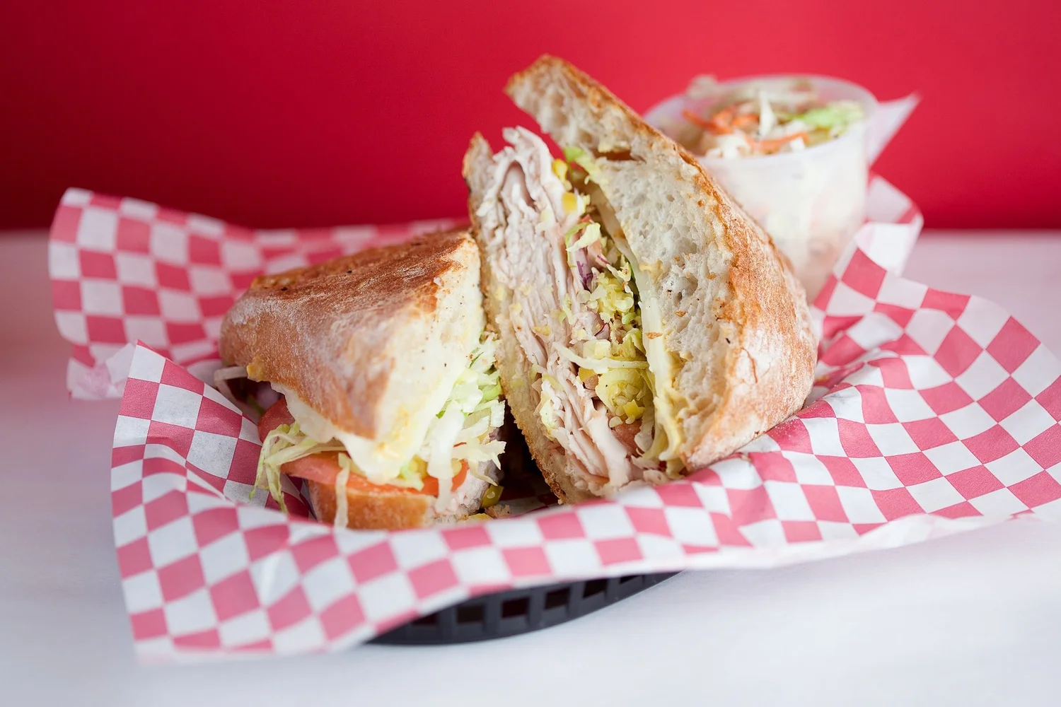 A generously stacked Charlie’s Deli sandwich in a red-and-white paper-lined basket