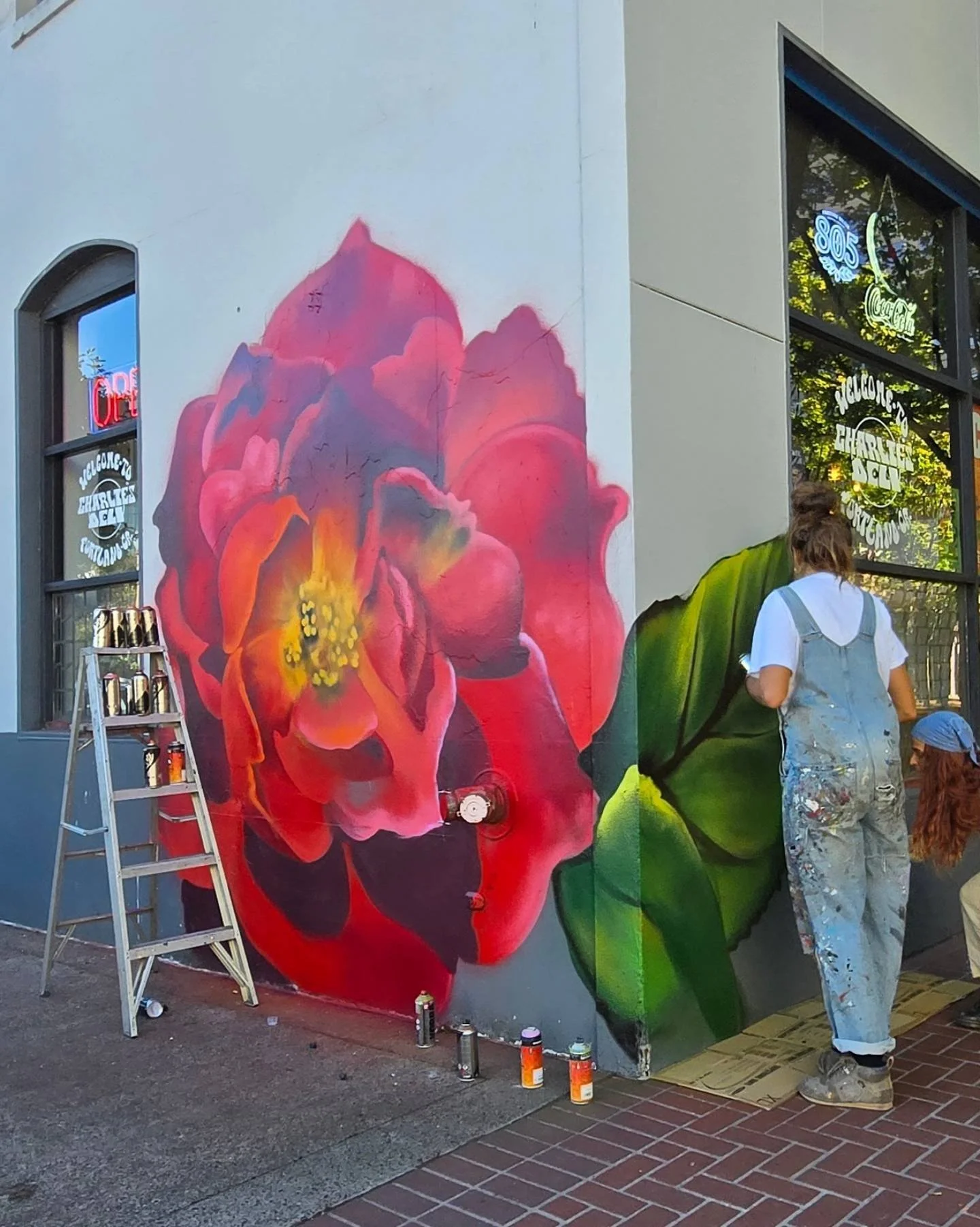 The artist with the bright floral mural at Charlie’s Deli
