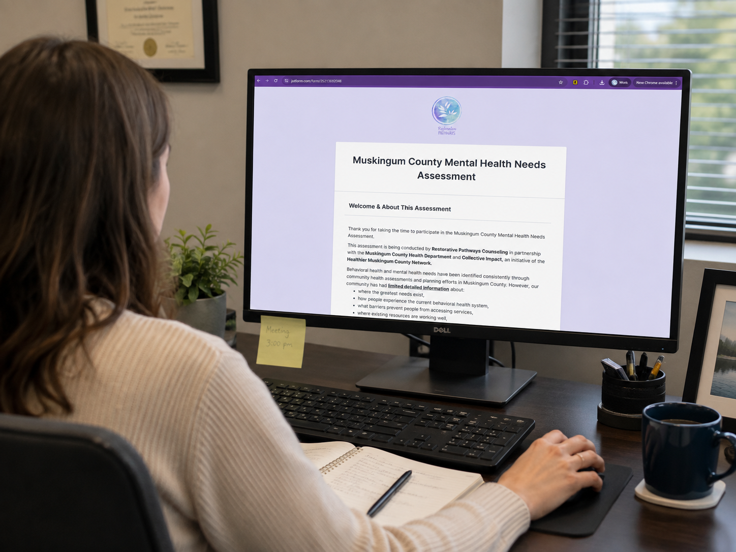 A woman sits at her desk looking at the community health assessment on her computer screen
