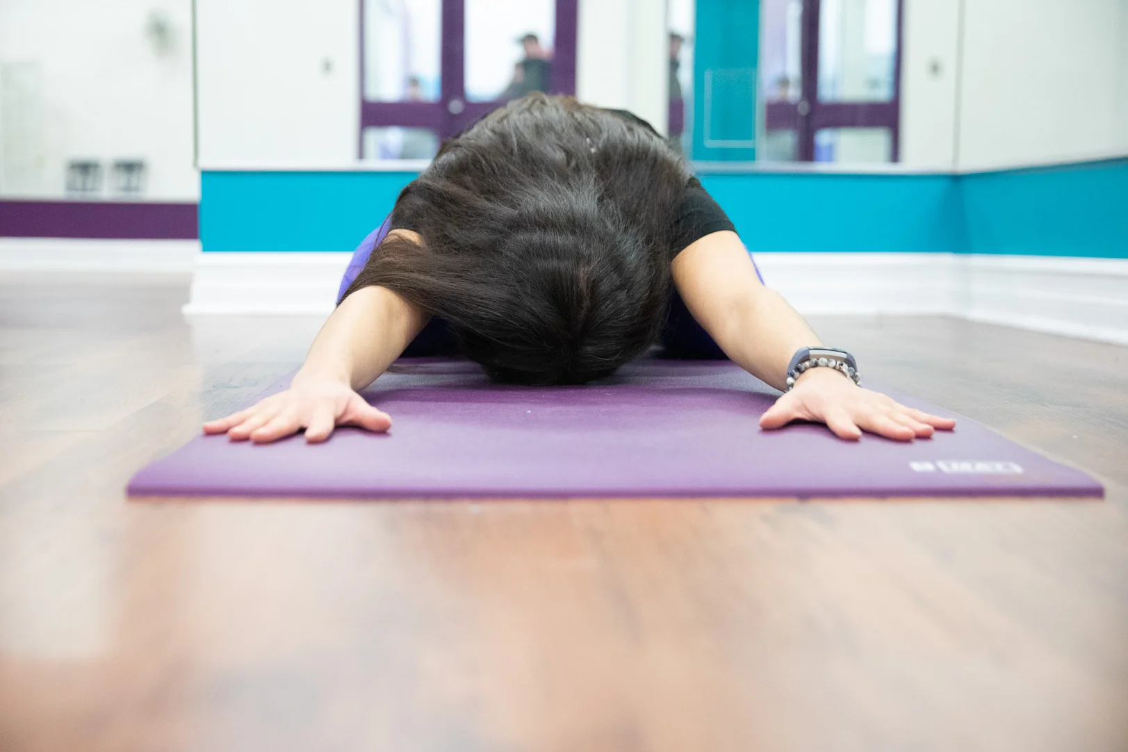 An example of a child’s pose. Hips tilted back towards the heels, arms stretched out overhead to open up the back and chest, resting the forehead on the mat or a block can be used to support as well.