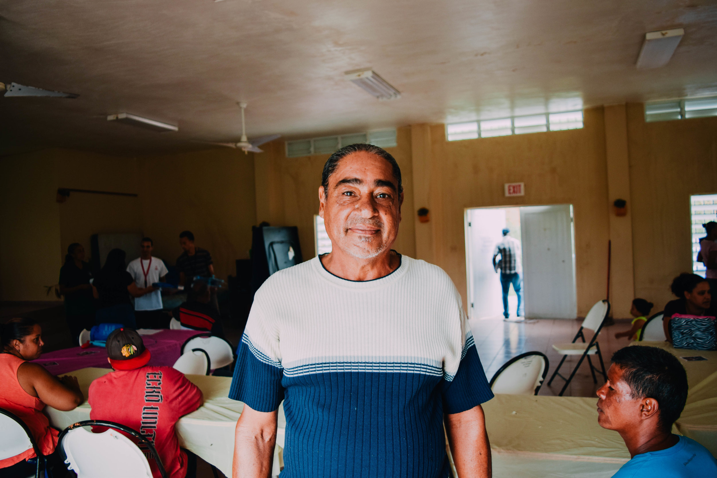 November 16, 2017. Juncos, Puerto Rico. A man stops for the camera as he receives an aid bundle from Mercy Corps working through community partner LTRG (Long Term Recovery Group). The bundle included a $100 prepaid Mastercard, Lifestraw water filter, and a Solar Lamp by Total.