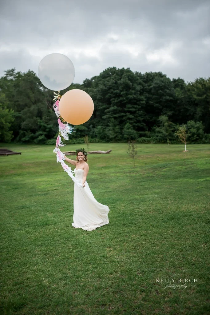 Bride holding large round balloons on the grounds of Historic Hope Glen Farm