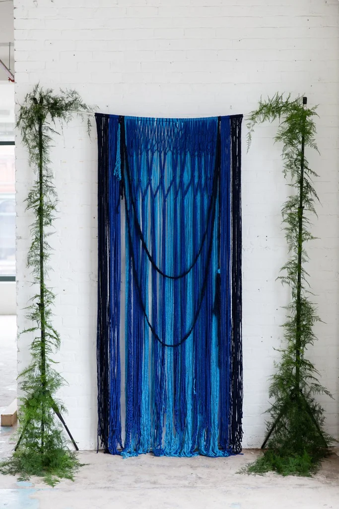 Creative ceremony backdrop made with yarn and greenery, as seen in Dainty Obsessions