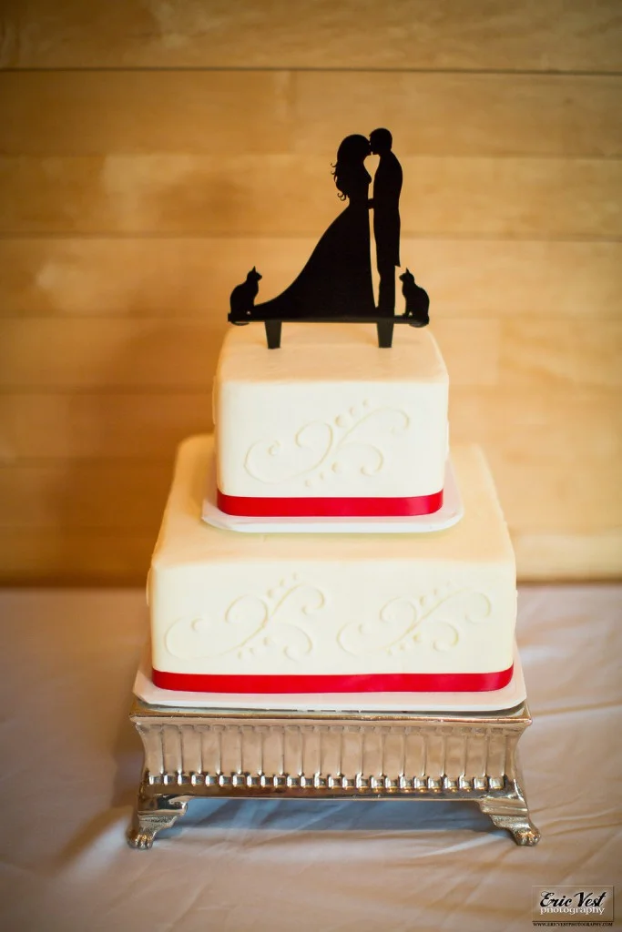 simple two tier wedding cake with red ribbon and custom cake topper