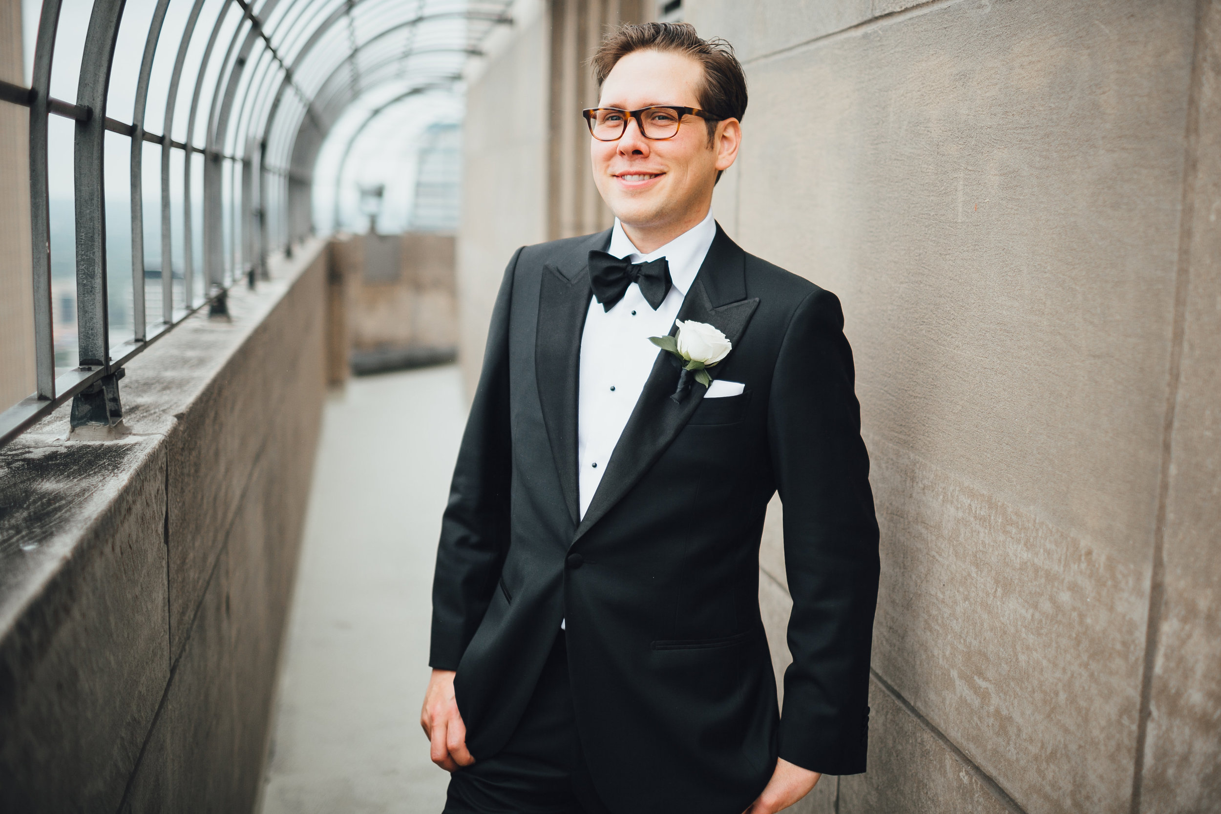 Groom smiling in black tuxedo and white rose boutonniere