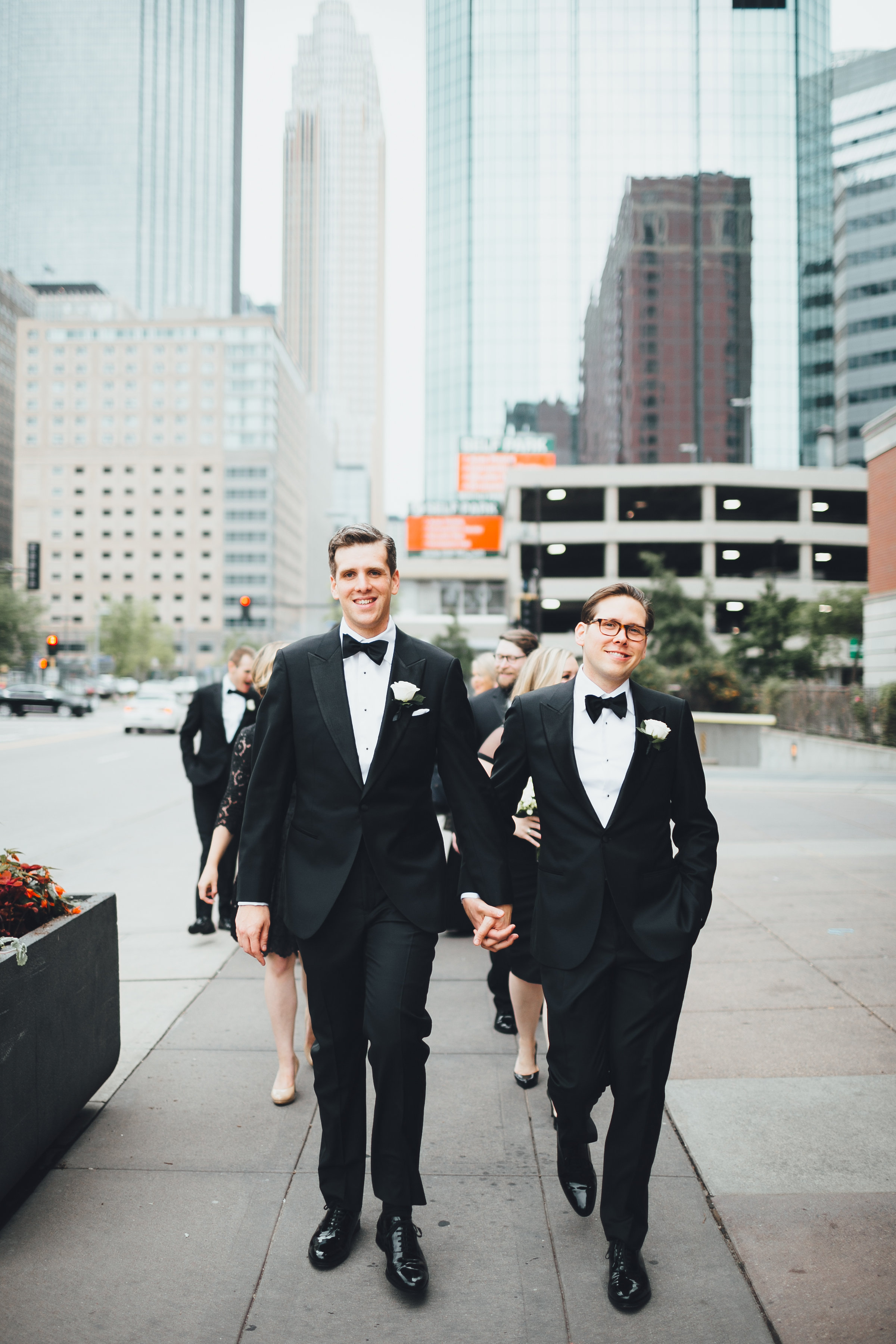 Grooms holding hands walking downtown