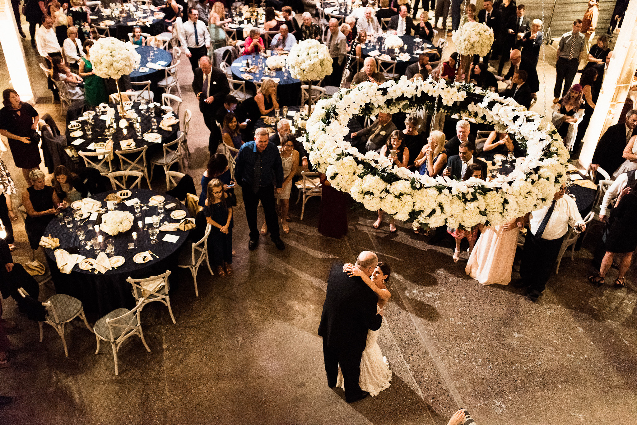 bride and groom under the hanging floral chandelier