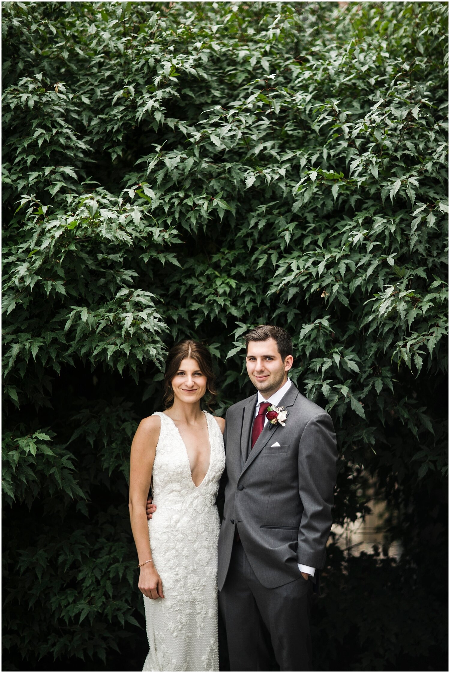  bride and groom posing with greenery background 