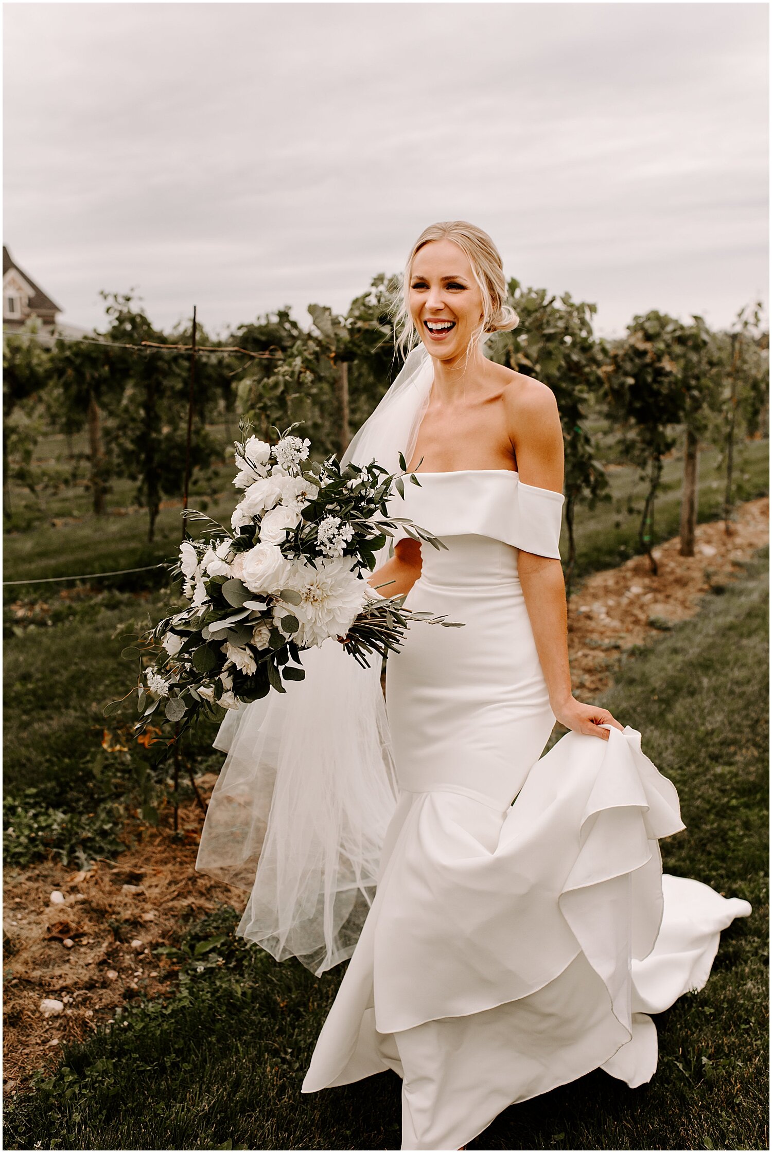  bride holding her bridal bouquet with white flowers and greenery 