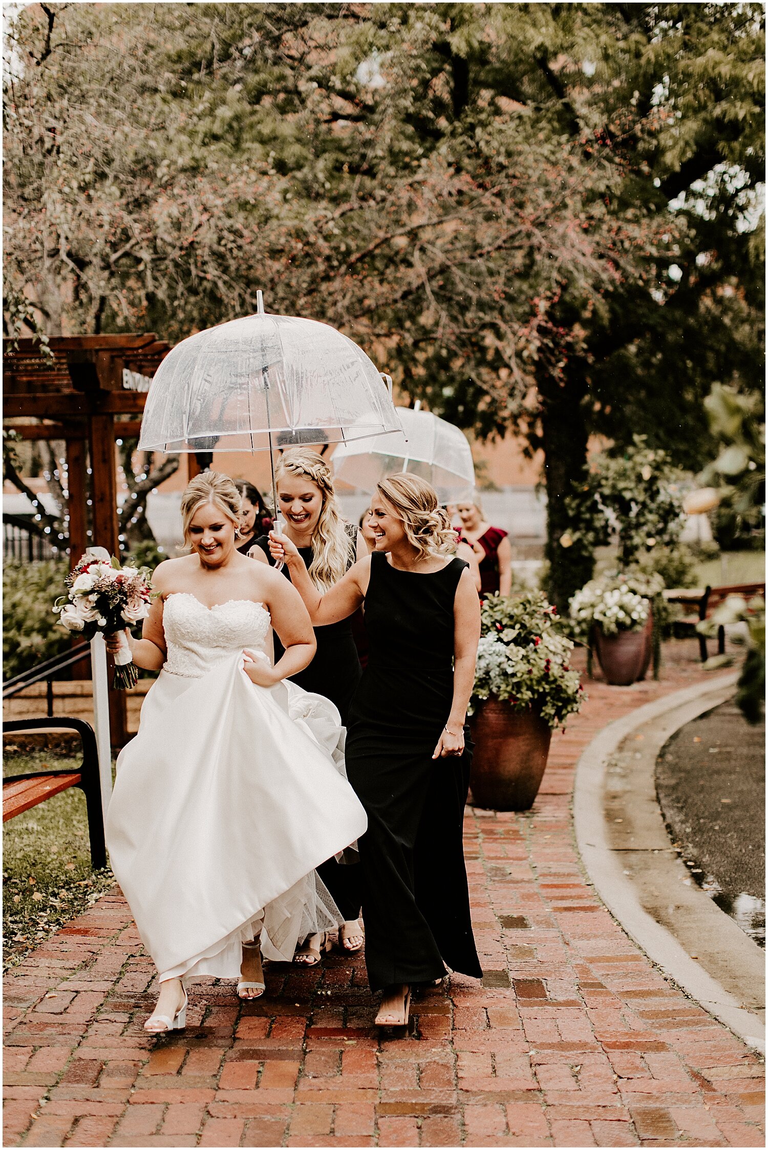  bride and bridesmaids walking to the ceremony with umbrellas 