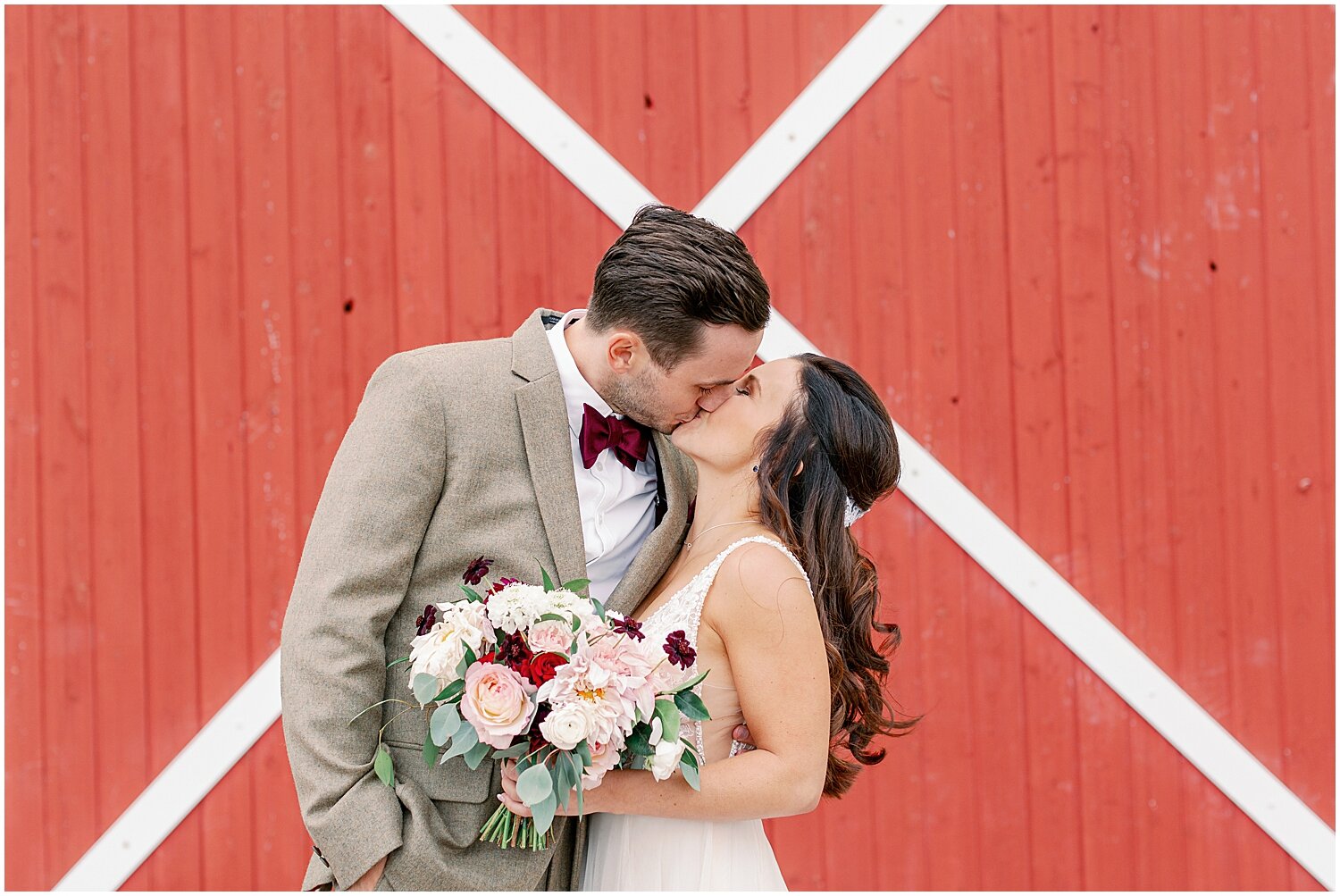  bride and groom kiss in front of a red barn in mn 