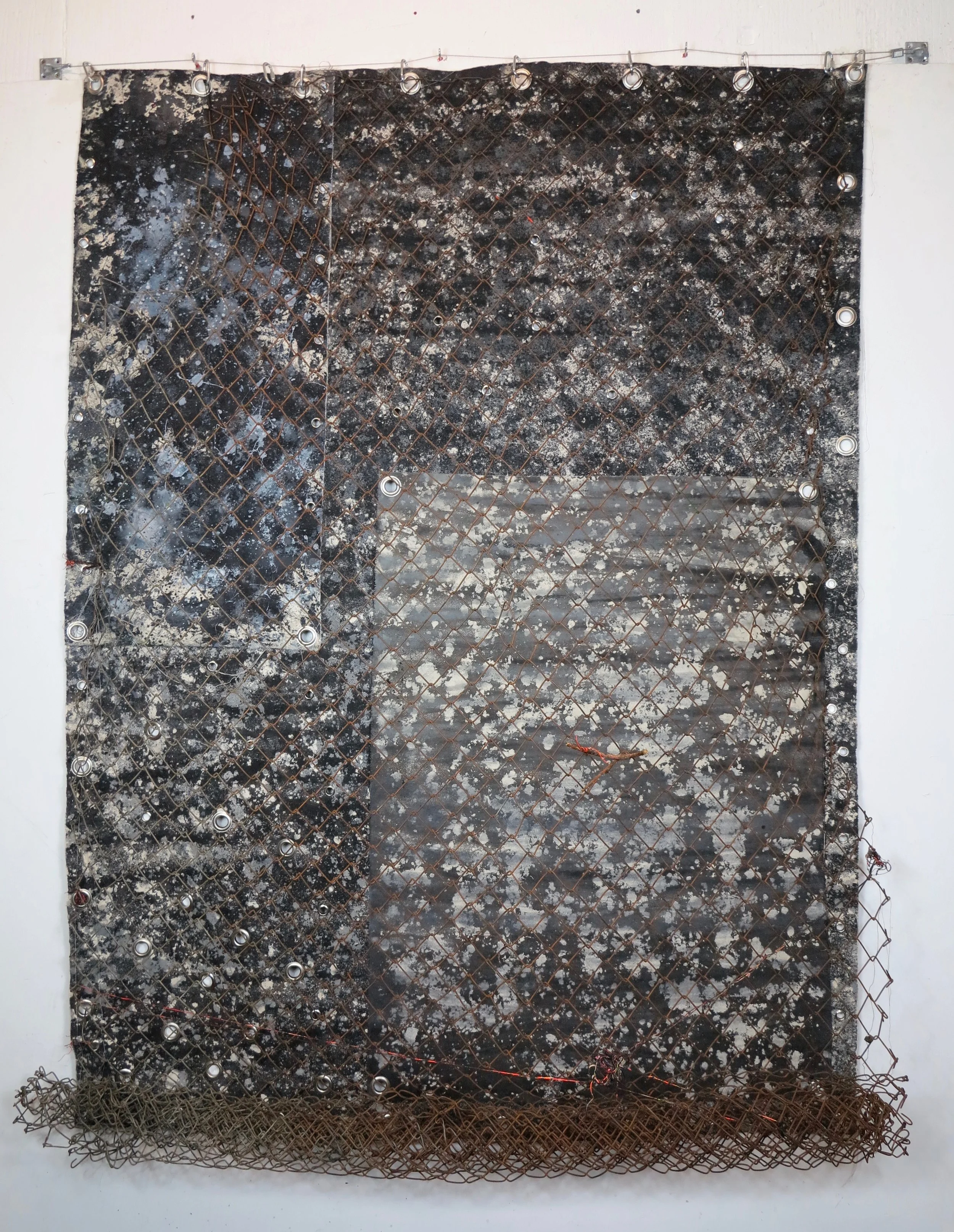 Theresa Got a Trap House. Spray paint, sand, gravel, cotton, diamond fence, eyelets, polyester, canvas and steel wire. 235 x 172 cm. The Silver Building, London 2018.