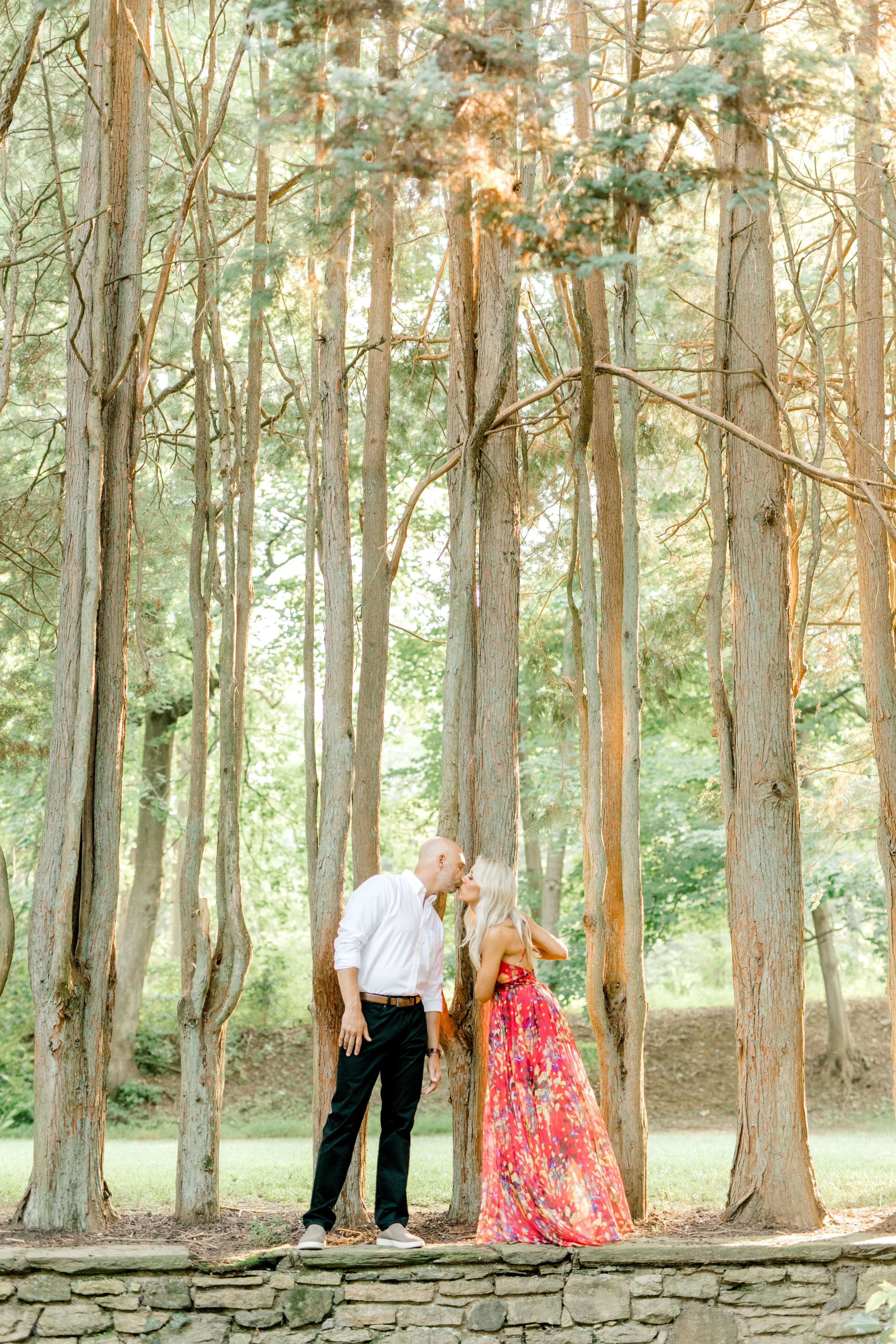 Liz and Bill share a kiss for their romantic sunset woodland engagement session at Parque at Ridley Creek