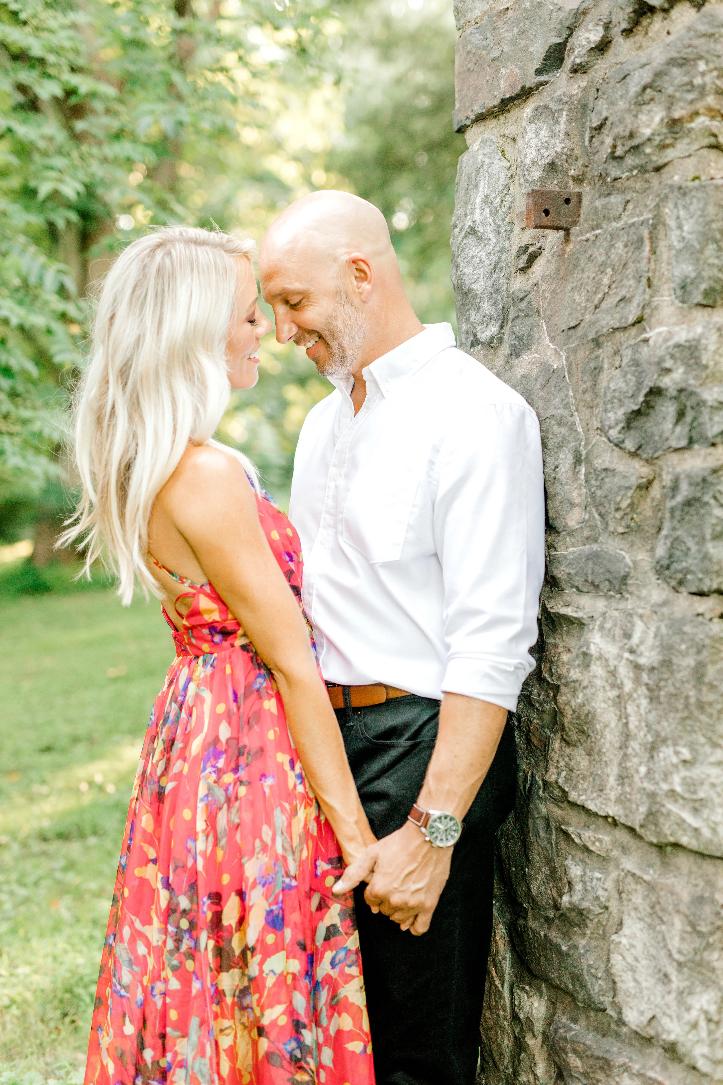 All snuggled up, we love the way Liz’s bright red dress pairs with Bill’s neutral color palette of black and white. The pop of floral print in the dress brings this classic color combo right into the summer for their romantic sunset woodland engagement session at Parque at Ridley Creek