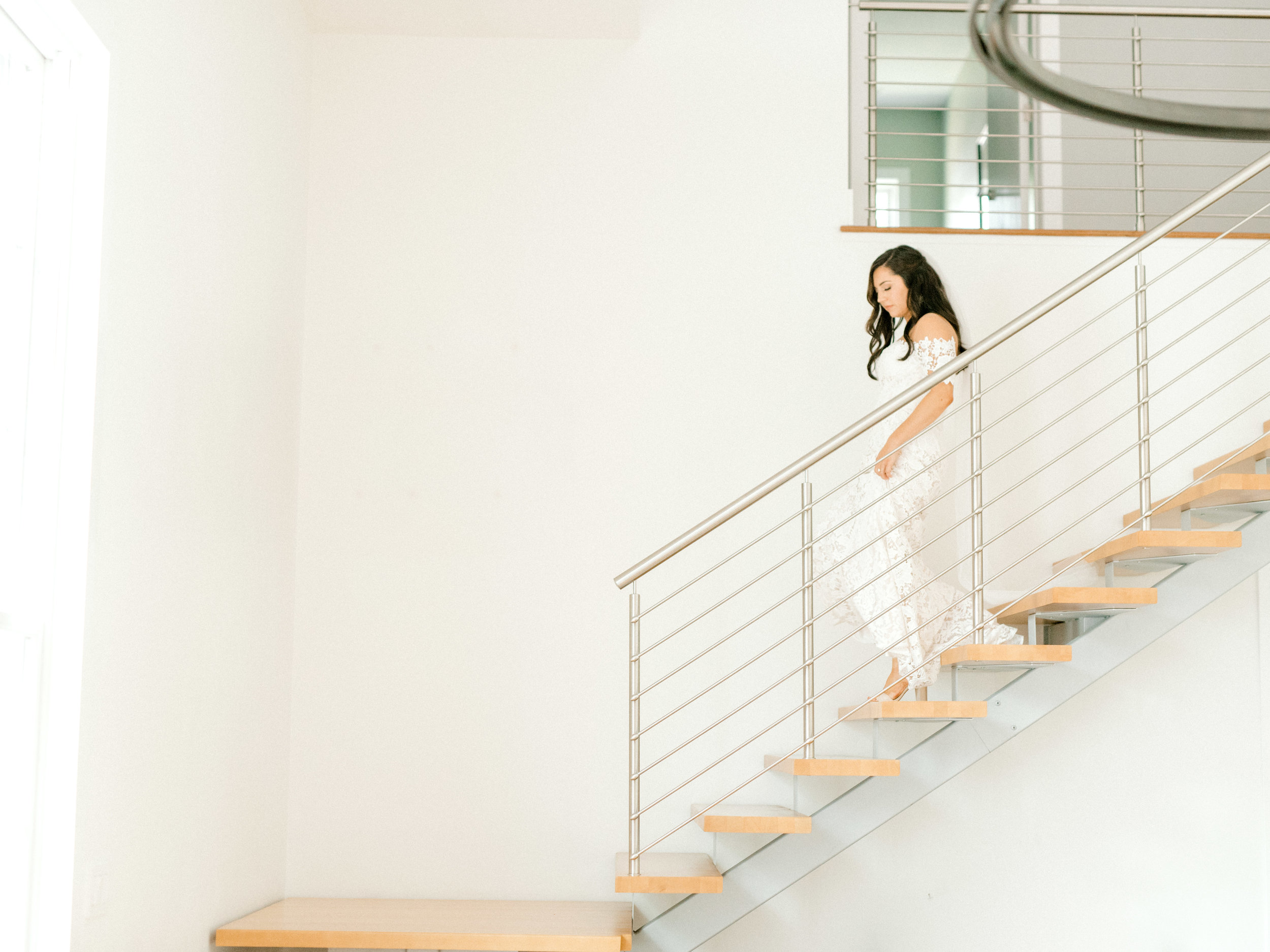 Lindsey descends the stairs of this light filled AirBnb as she heads to her bright and modern summer wedding at Hotel du Village.