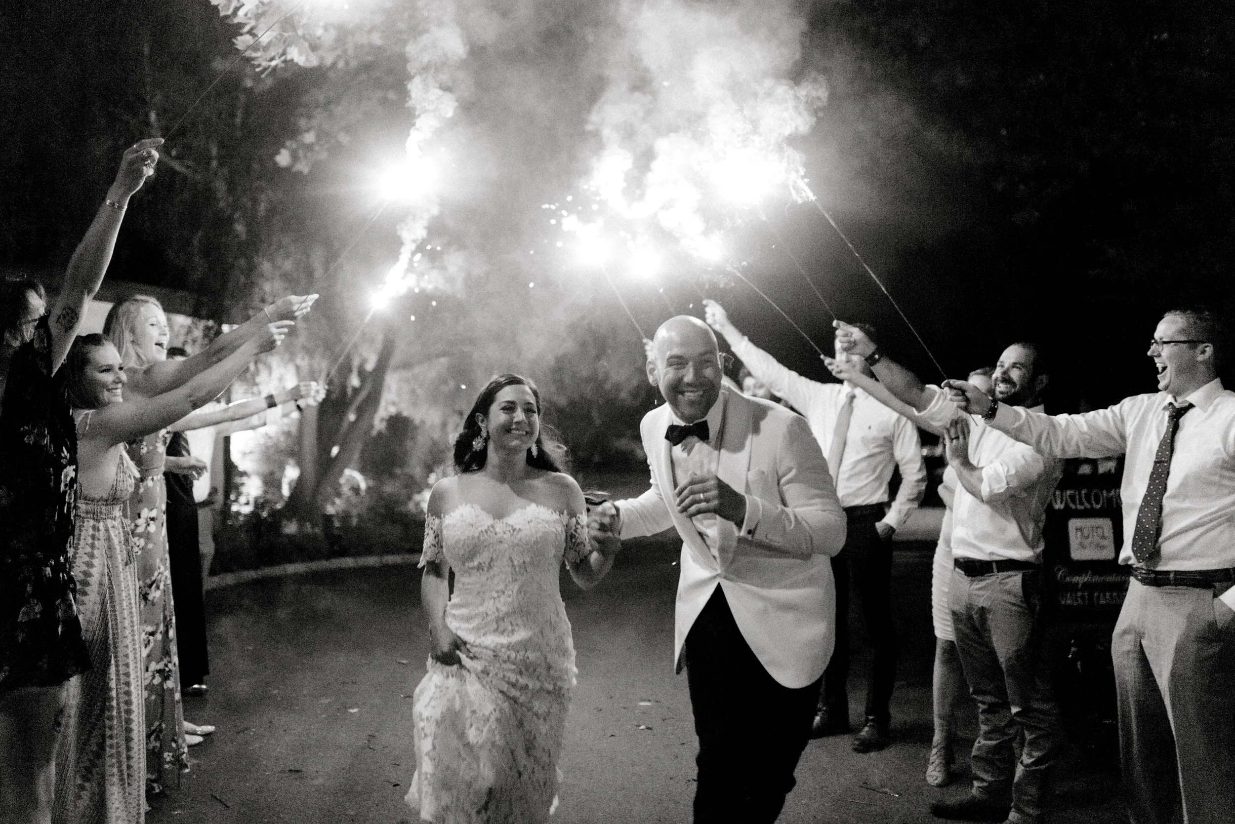 Happy as can be, Lindsey and James run through a line of sparklers to celebrate their amazing modern and bright summer wedding day at Hotel du Village.