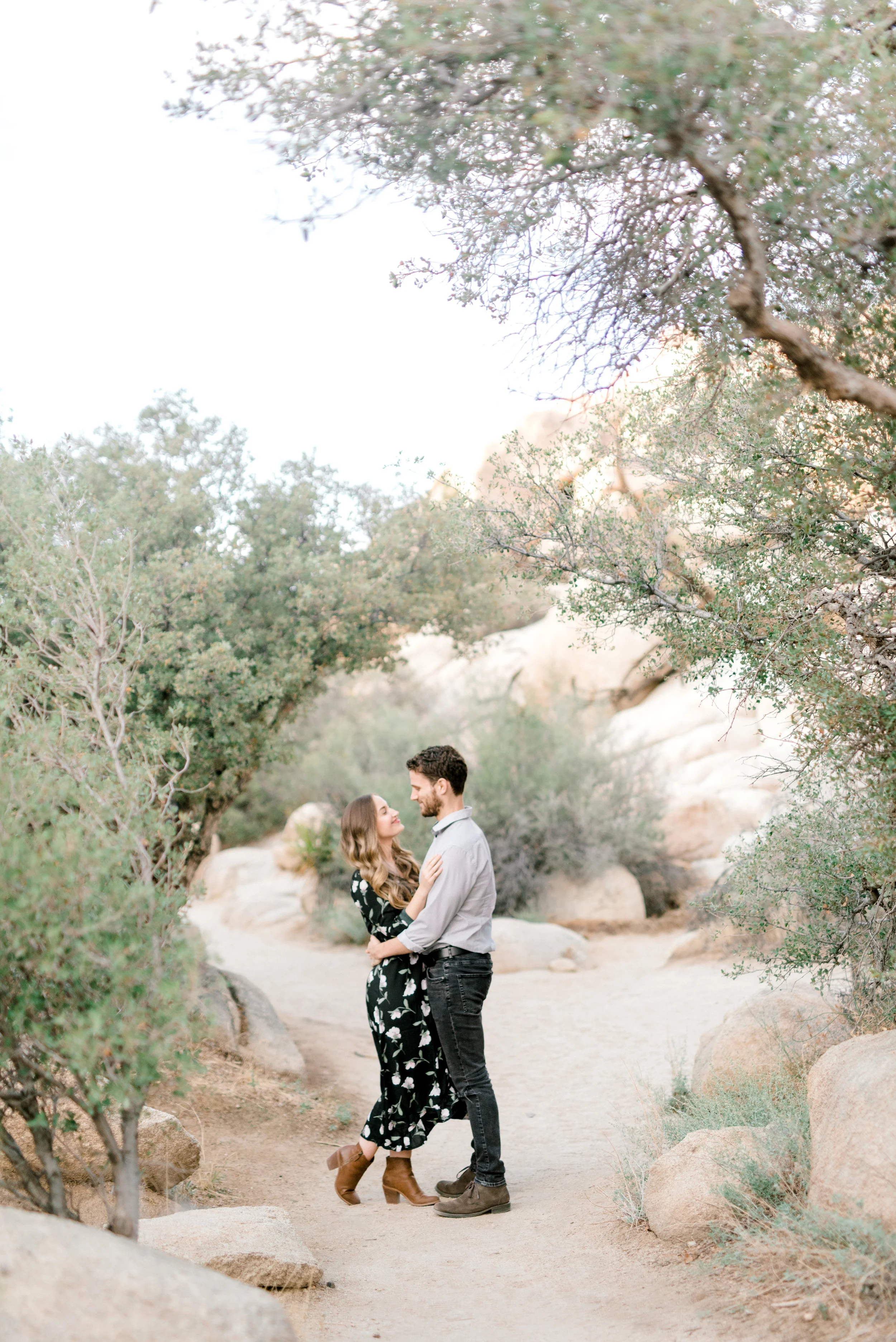 Jenna and Sam are perfectly framed in the soft green trees for their free-spirited desert engagement session in Joshue Tree