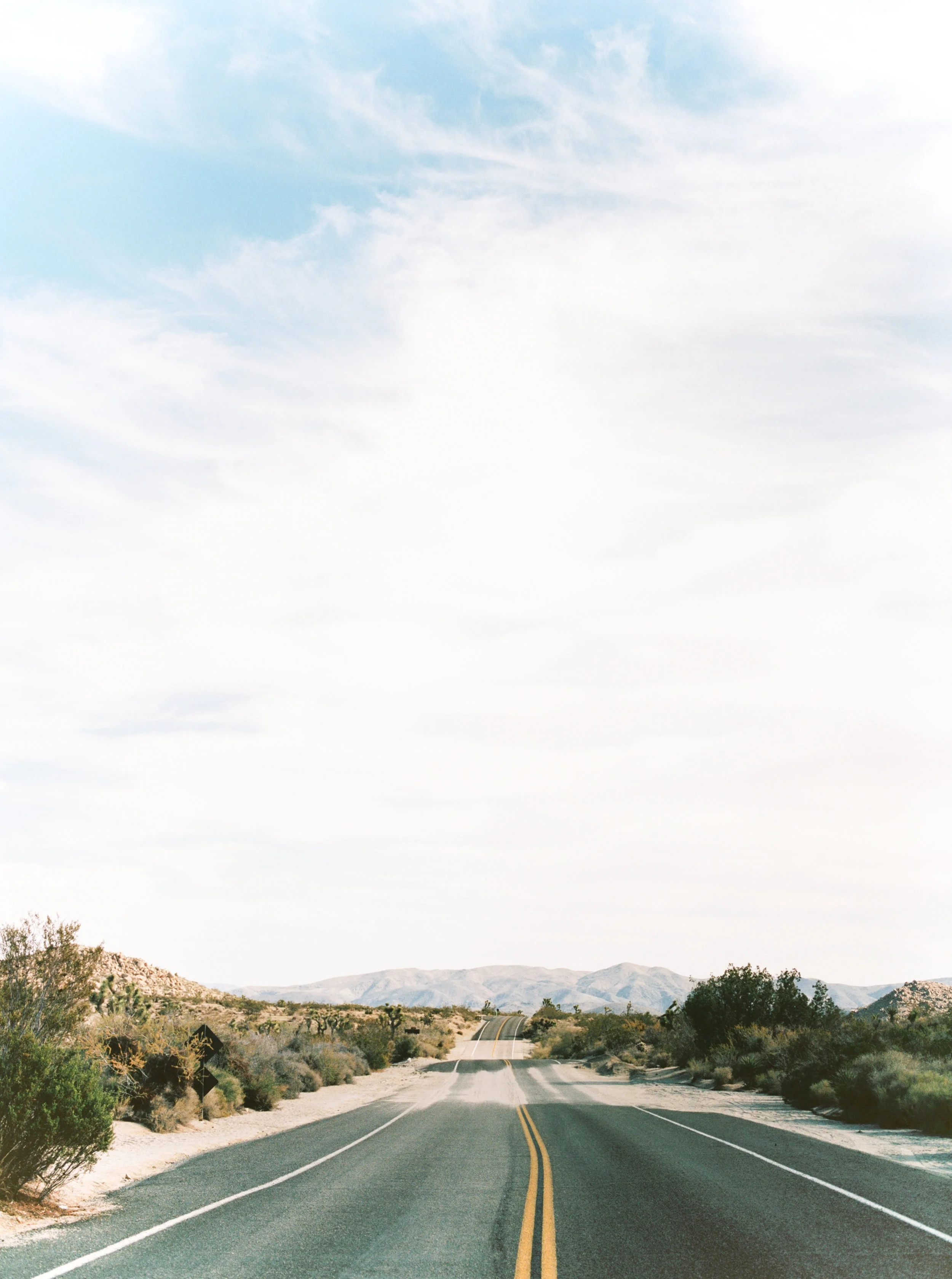 We just want to head off down the road toward those mountains in the distance at this free-spirited desert engagement session in Joshue Tree