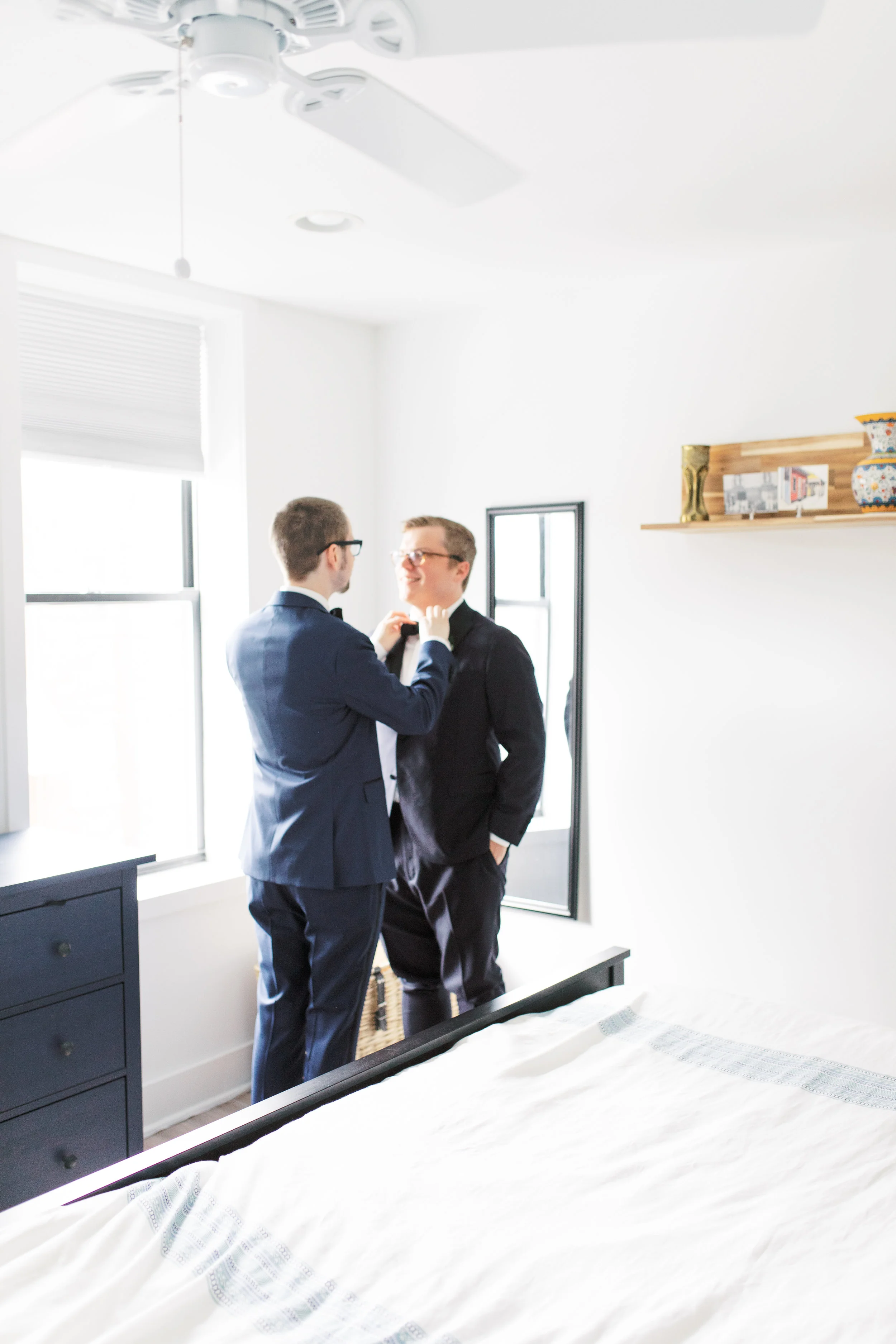 two grooms getting ready together in their home on their Philadelphia wedding day adjusting tie