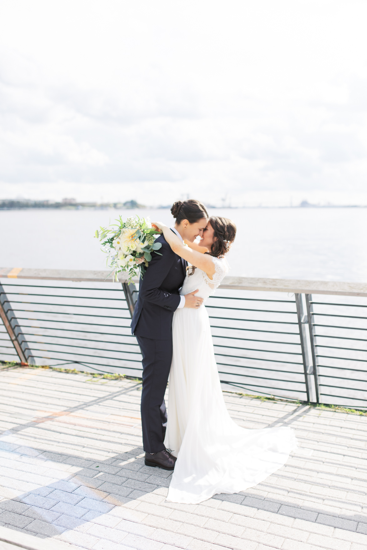 The happy couple share a kiss on Race Street Pier overlooking the Delaware River for their modern and elegant old city Philadelphia Power Plant Productions wedding. Power Plant Production wedding photographer