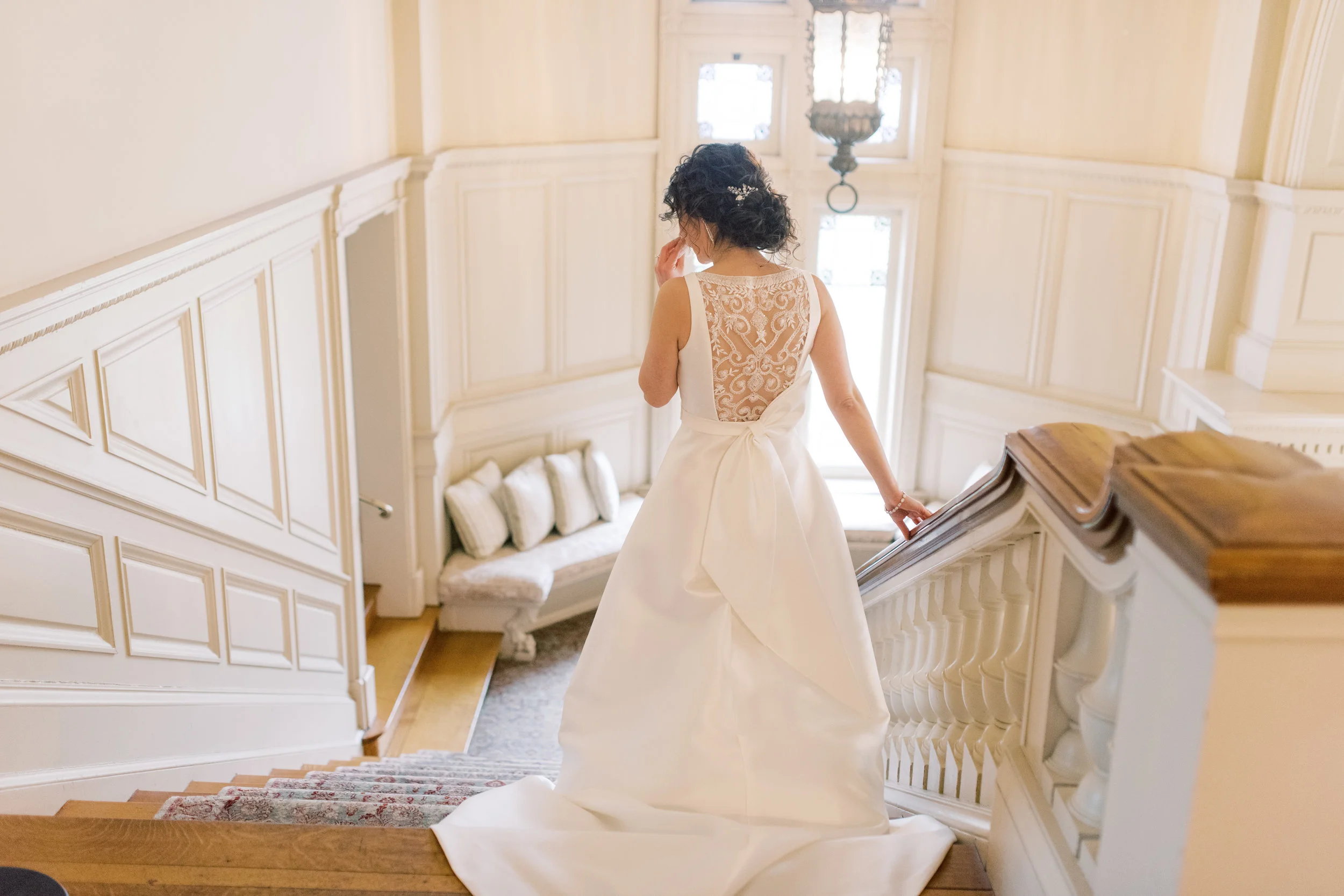 Angjela heads down the staircase for her first look for her romantic and classic wedding day for their french inspired green and white Cairnwood Estate wedding