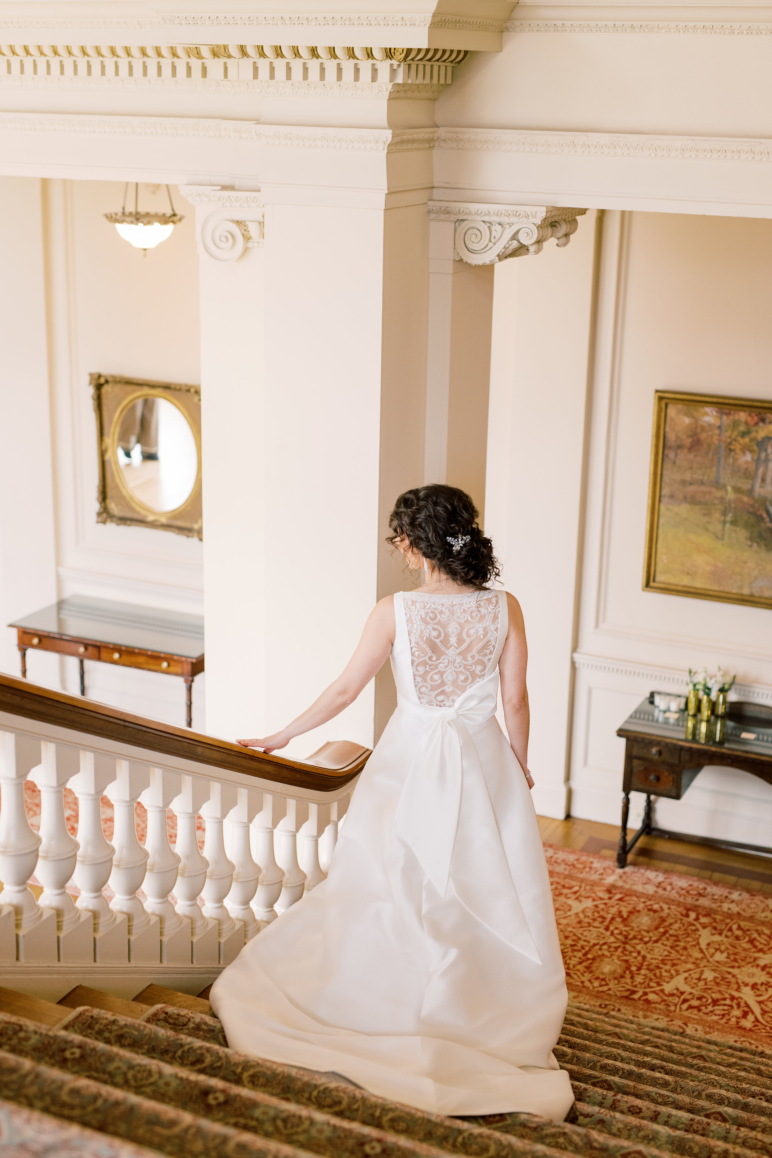Our bride heads down the grand staircase as she is about to see her groom for the first time at their romantic and classic wedding day for their french inspired green and white Cairnwood Estate wedding