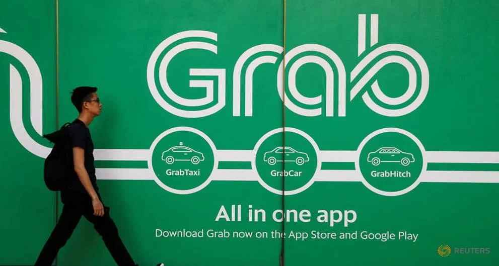 A man walks past the Grab logo, photo from the Straits Times and Reuters